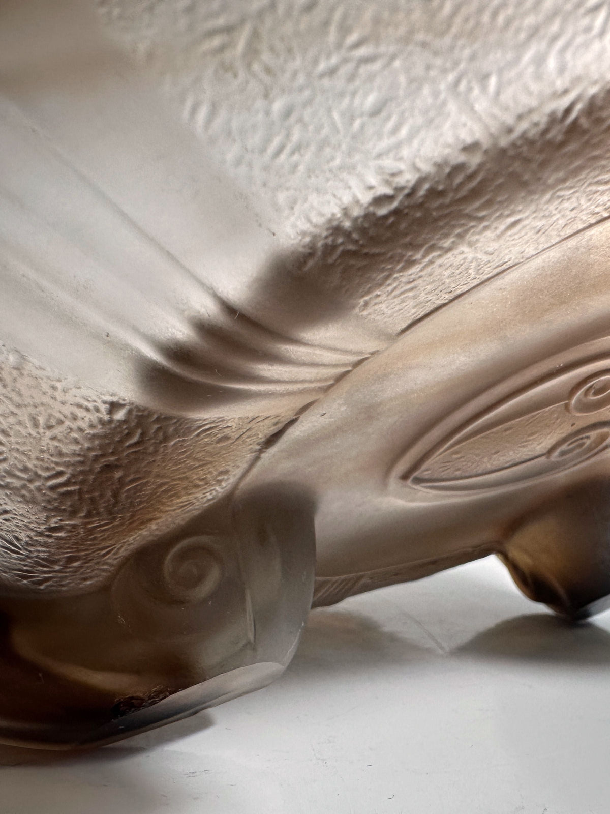 Close-up of a German Art Deco Cloud Glass Bowl by Dodo Vintage, circa 1930, showing textured frosted glass with swirling and oval patterns, a soft brown tint, and translucent areas against a white background.