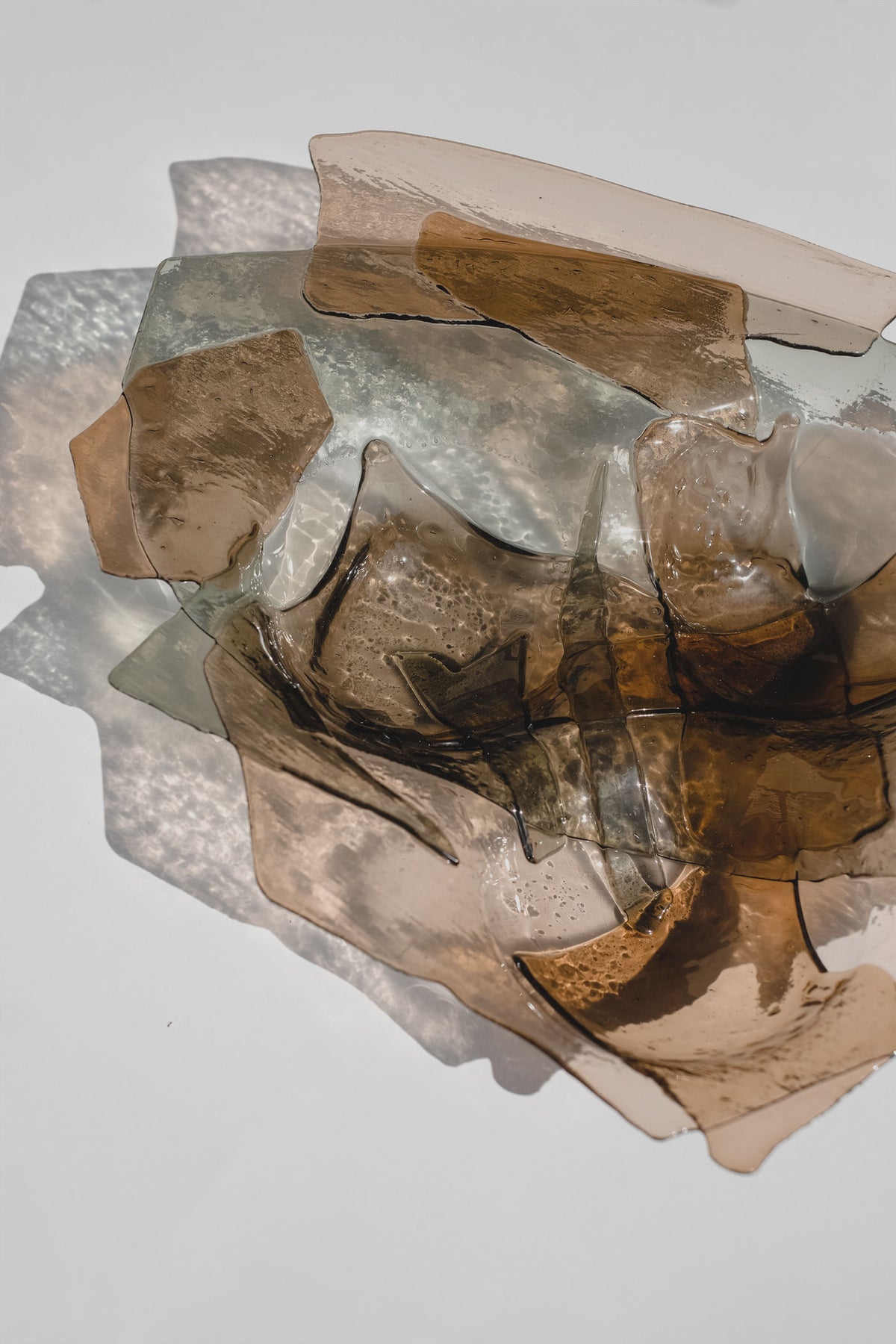Broken handmade glass bowl fragments showing amber and clear tones