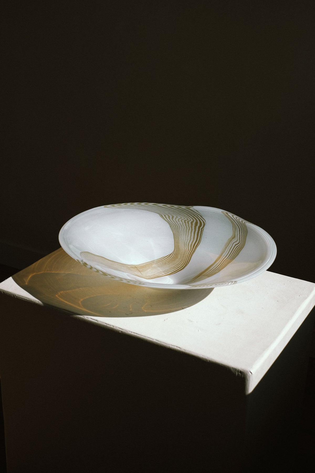 Large blown glass bowl with gold swirl pattern on marble surface