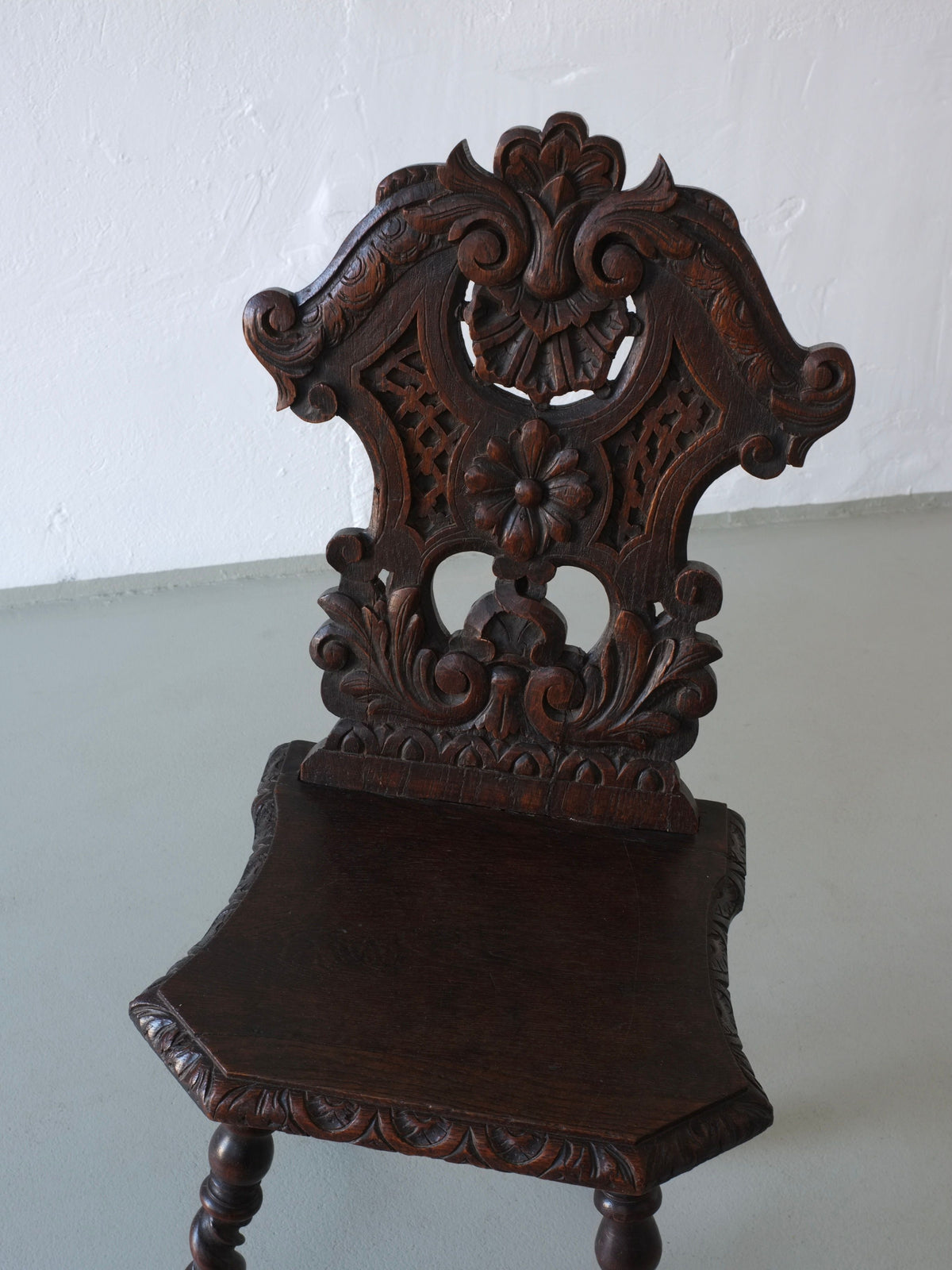 Ornate carved back detail of dark oak antique chair 1900s