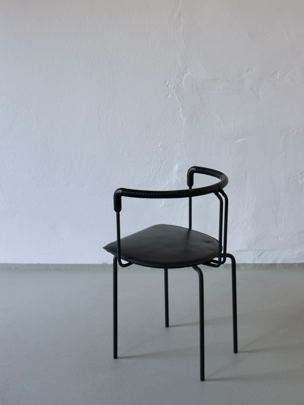 Single postmodern black leather armchair with curved backrest detail