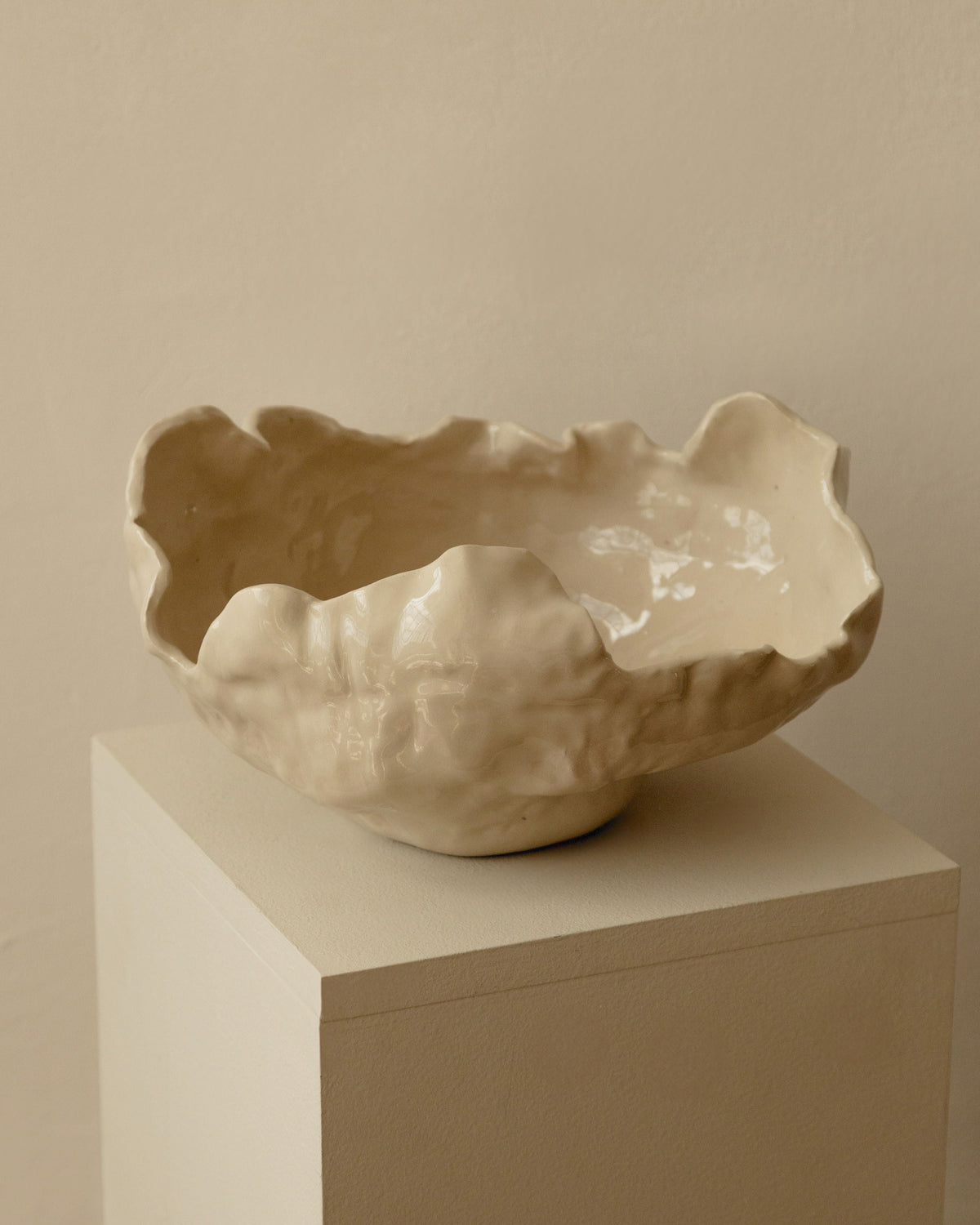 Cream ceramic Modica bowl with organic sculptural edges on white pedestal