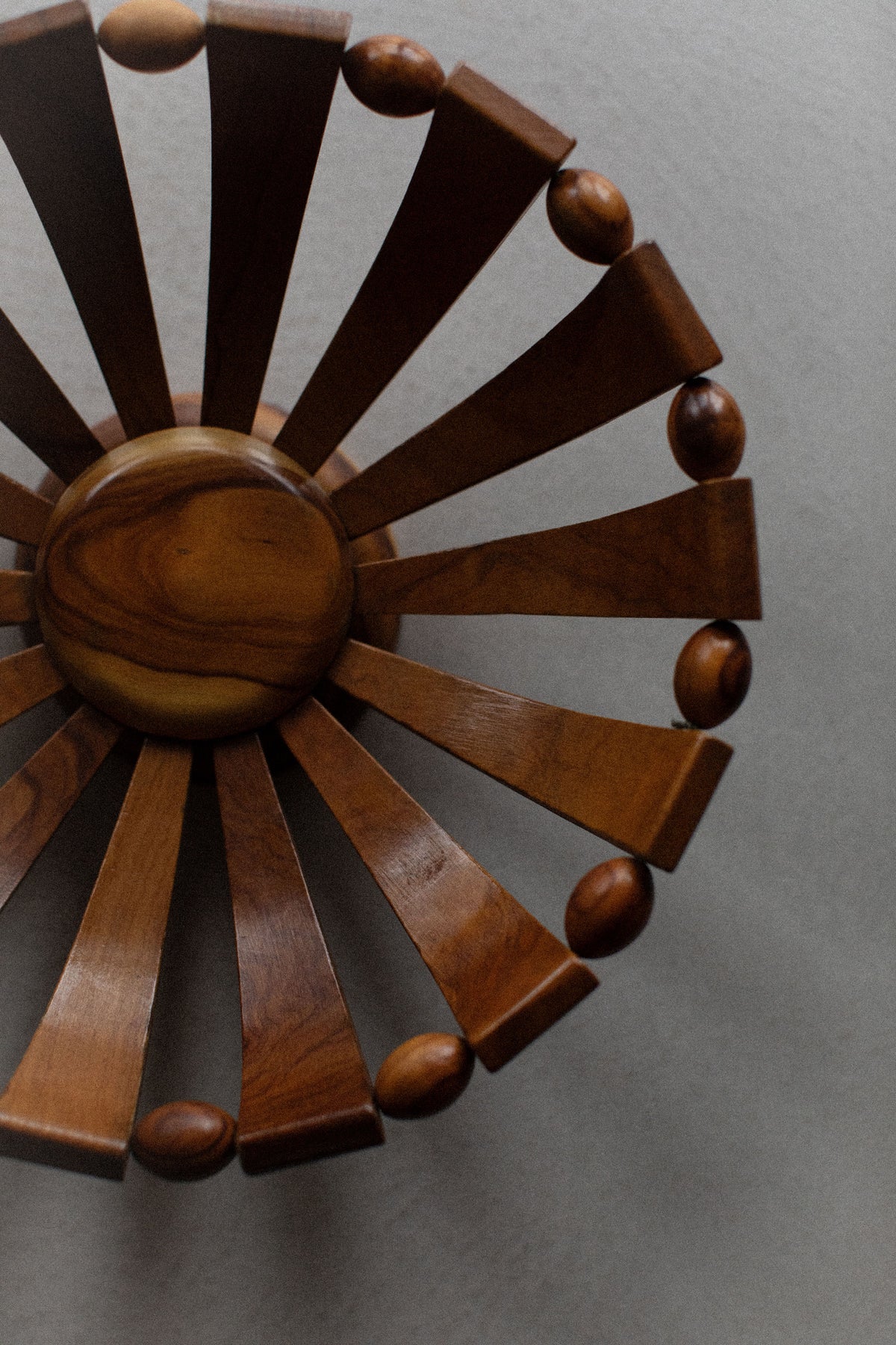 The 1950's Wooden Bowl by Out For Lunch, featuring curved radial spokes and oval knobs, highlights its natural wood grain from a top view against a light gray background—ideal for adding rustic charm to your decor.