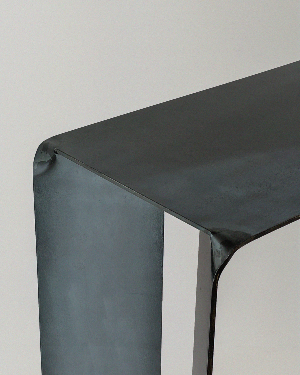 Corner detail of Hiro steel console showing curved edges and joints