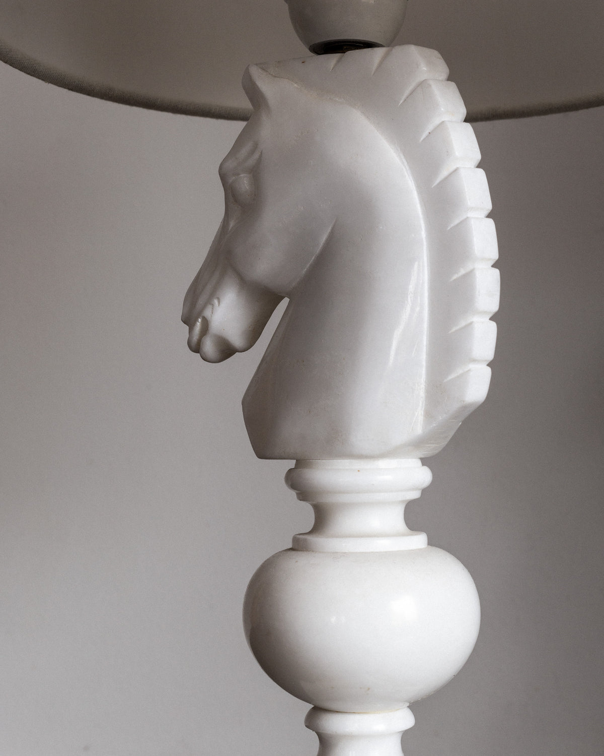 The Spigel Italian Alabaster Chess Knight Table Lamp (1970s) features a hand-carved white base shaped like a horse's head chess piece, complete with a detailed mane, set against a neutral background.