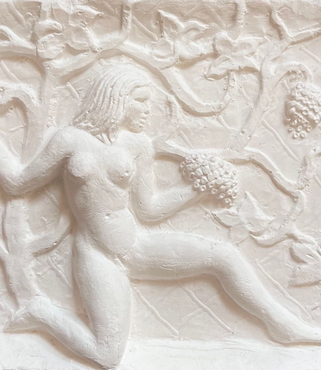 The midcentury plaster relief by Bo Fjaestad for Médecine features a nude figure holding grapes amidst vine-like patterns and leaves, evoking the lushness of a tropical garden with its textured surface enhancing the intricate vine motifs.
