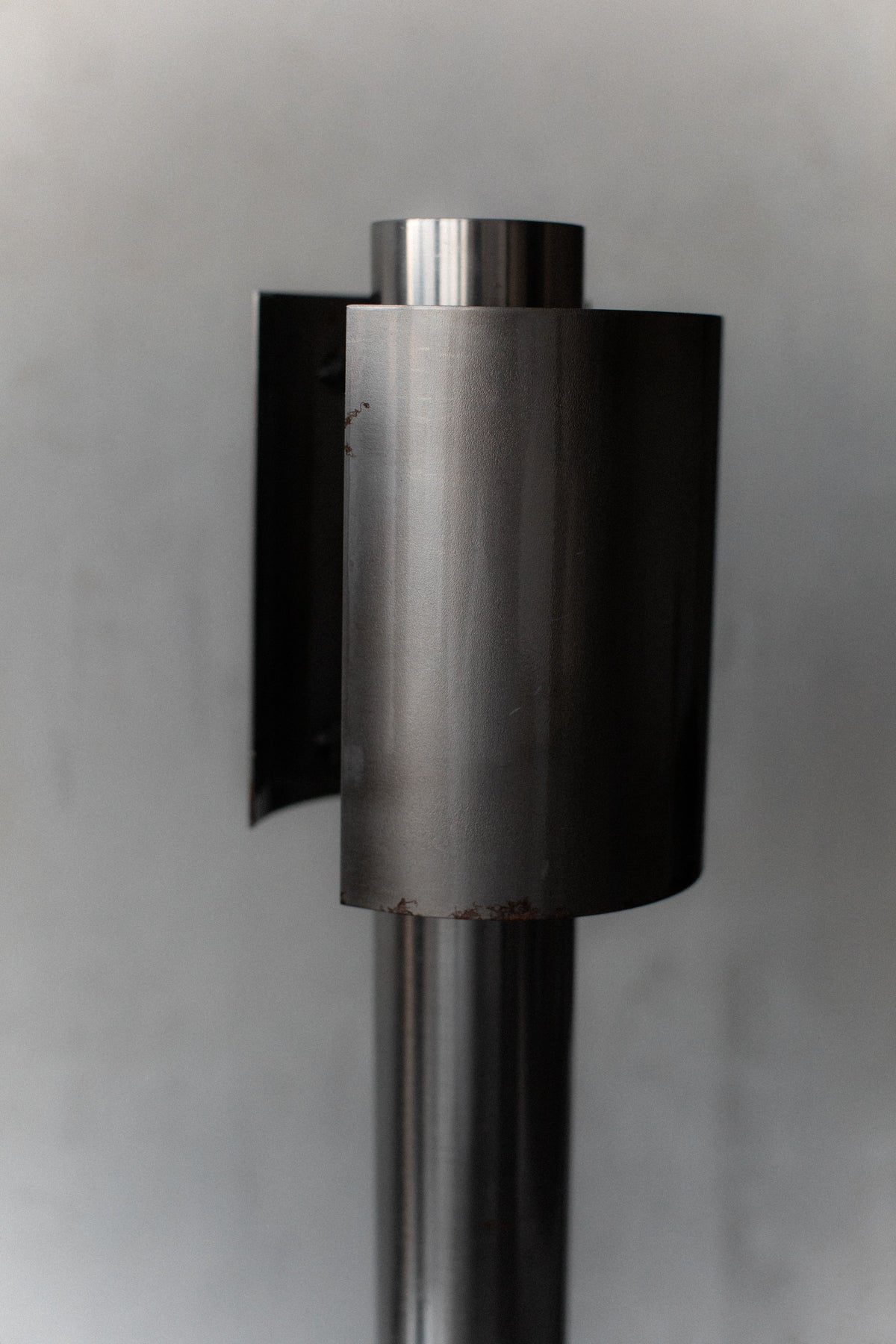 Close-up of the 1960's Space Age Lamps by Out For Lunch. The modern, cylindrical metal design with smooth surfaces stands against a gray background, showcasing vertical and horizontal elements that subtly reflect light in this timeless piece.