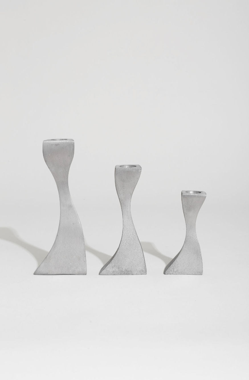 The Villa Wavy Candleholder Set features three silver-toned metal holders of varying heights, arranged in a row on a plain white surface against a white background.