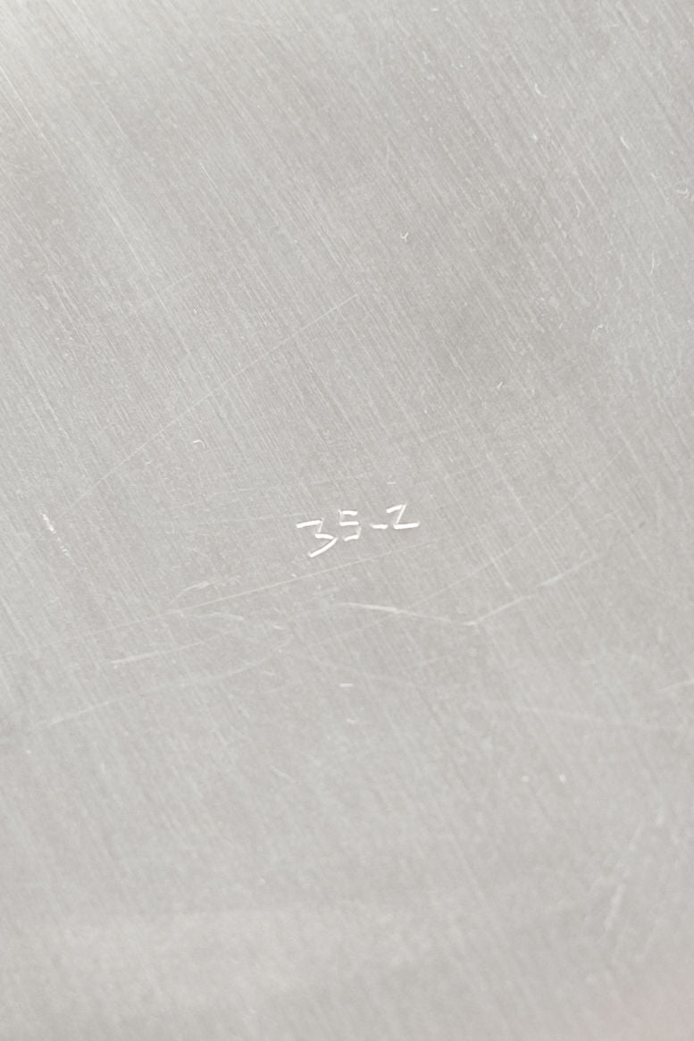 Close-up of a large silver-plated dish by septembre studios, featuring a scaled rim and fine scratches on its light gray, brushed metal surface. "35-Z" appears in white text at the center.