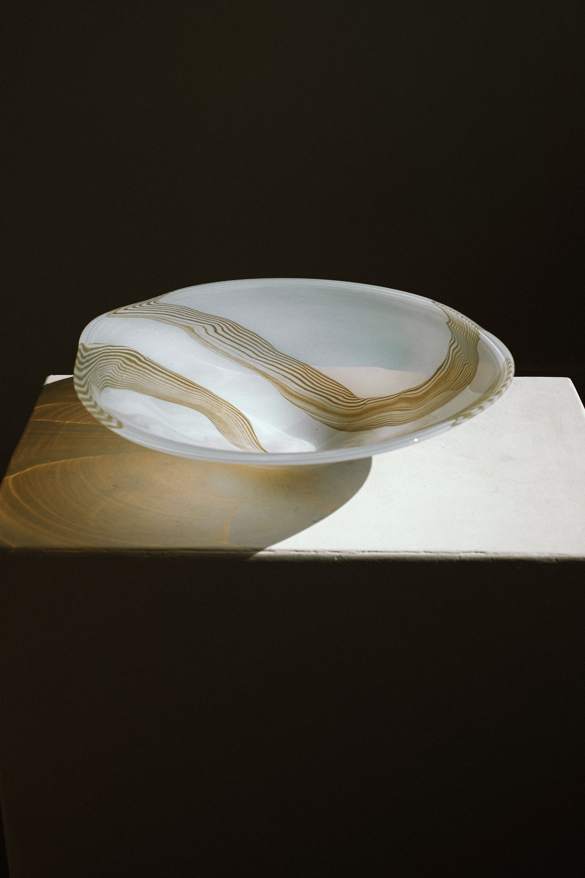 Large blown glass bowl with golden swirled pattern on marble surface