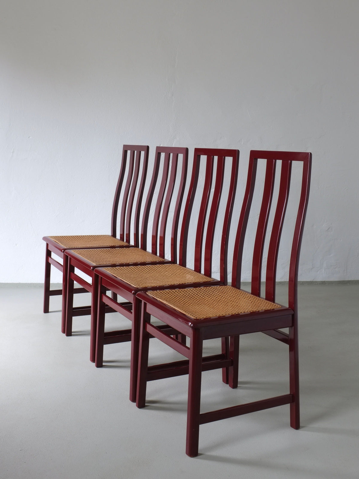 Four glossy wine red cane seat chairs in row, Italian 1970s design