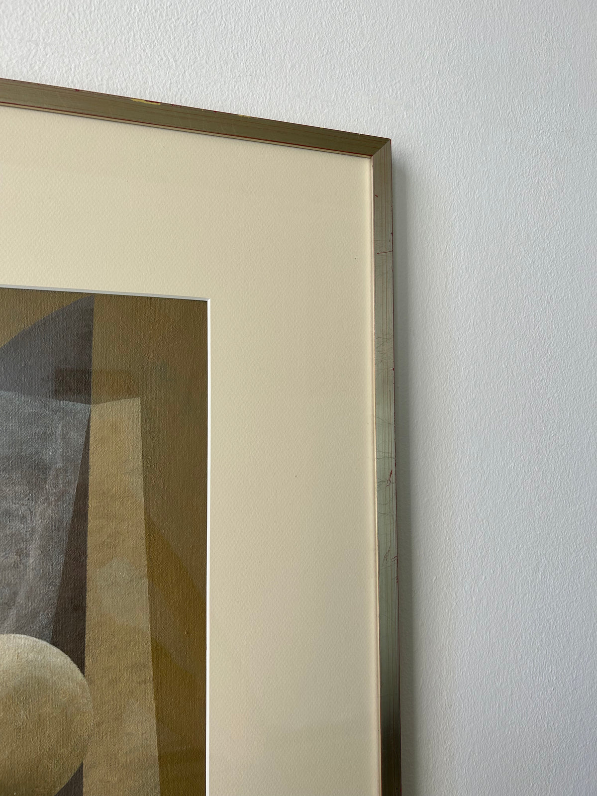 A close-up of an acrylic painting in a vintage frame hanging on a white wall. The "New Gold Dream" Painting, 2023 by Iris Bavelaar, features geometric shapes and muted earth tones, including shades of brown, beige, and gray.