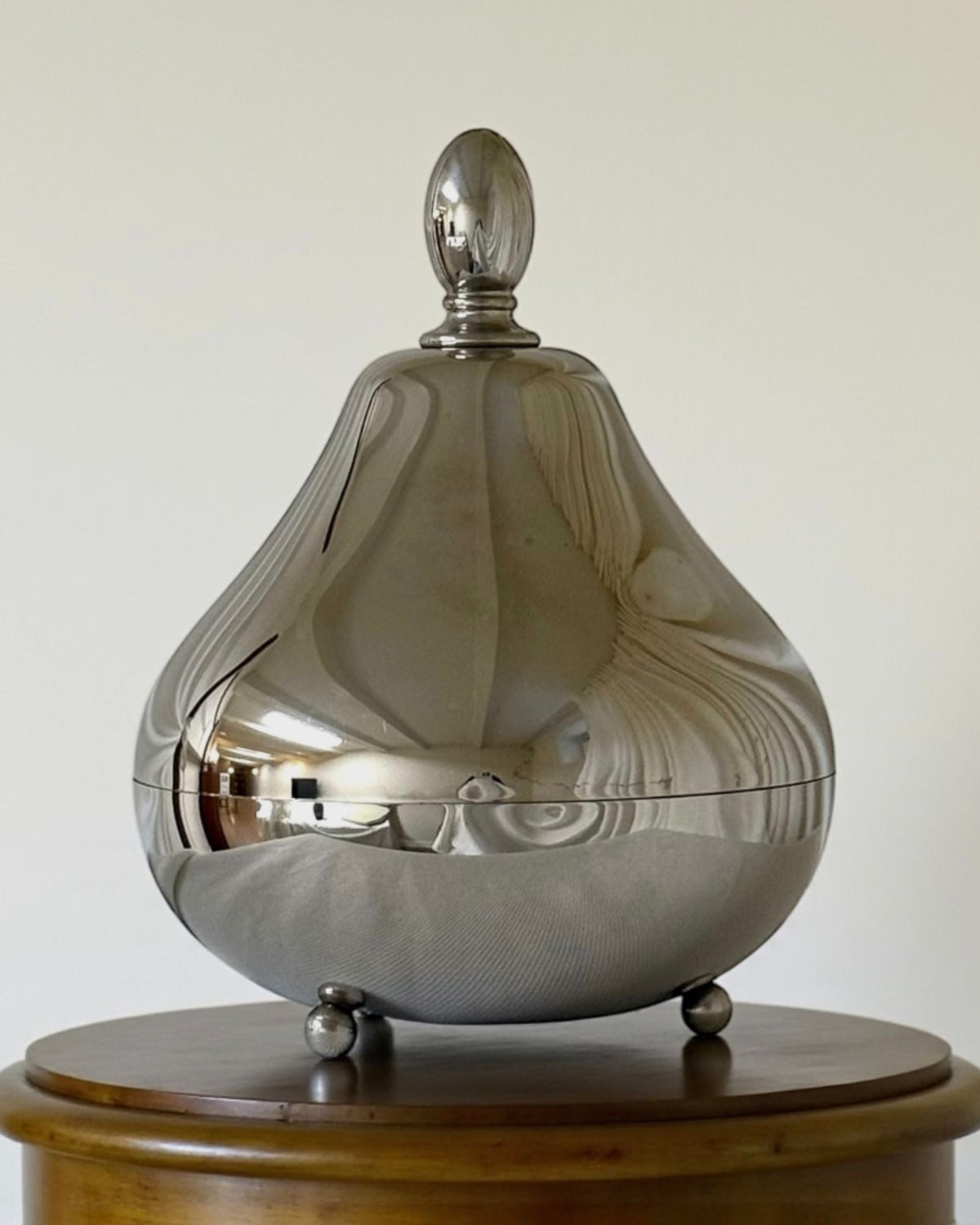 Polished silver pear-shaped serving vessel with domed lid on feet