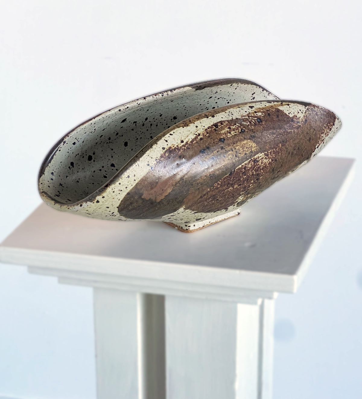 Curved ceramic sculptural dish with speckled earth-tone glaze detail
