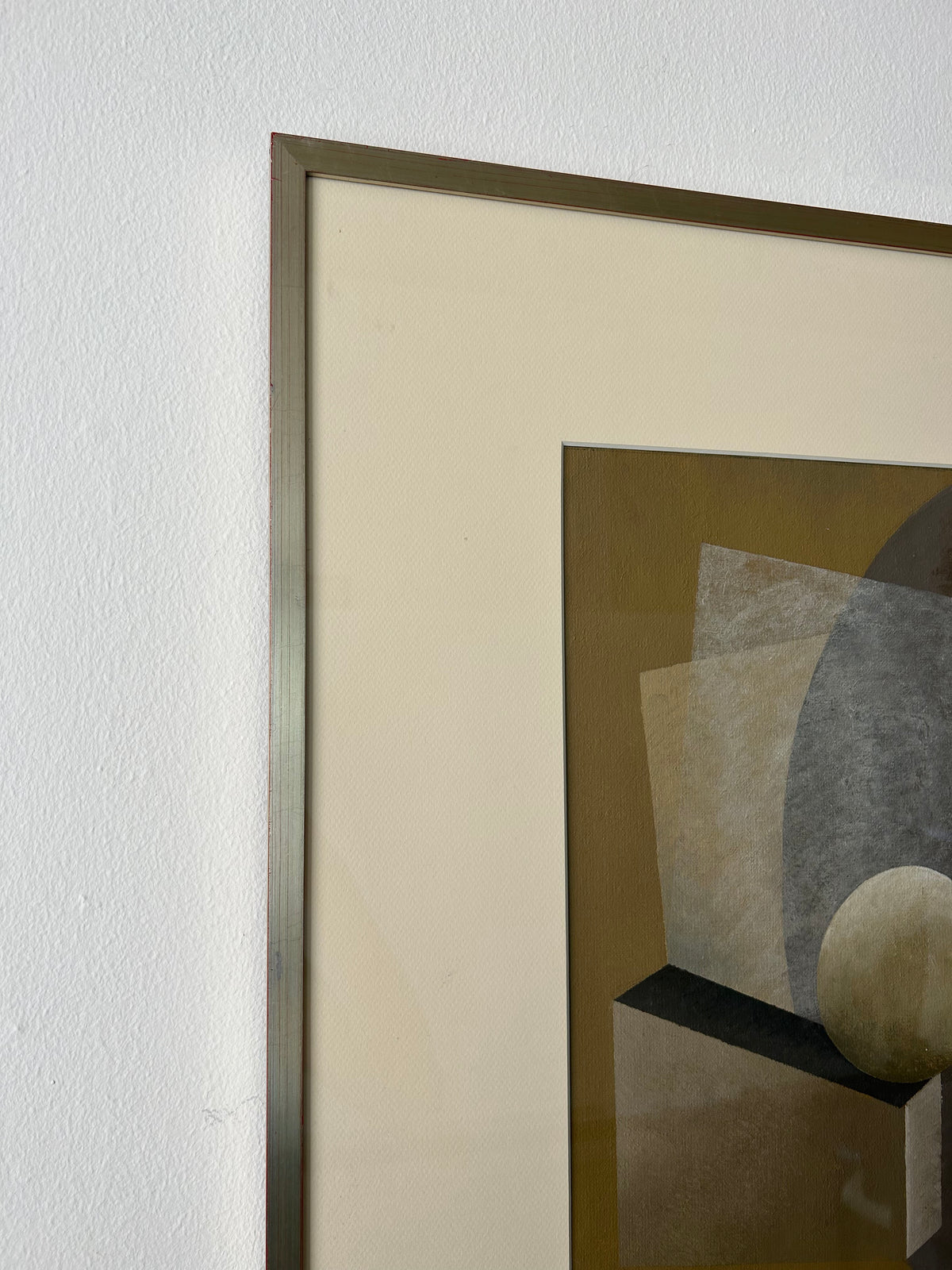 A close-up of a framed abstract artwork featuring geometric shapes. The left side of the vintage wooden frame and a portion of the "New Gold Dream" Painting, 2023 by Iris Bavelaar are visible. The background includes a sphere, a rectangle, and a partial circle in muted tones of brown and gray. Artwork measures 50x60cm.