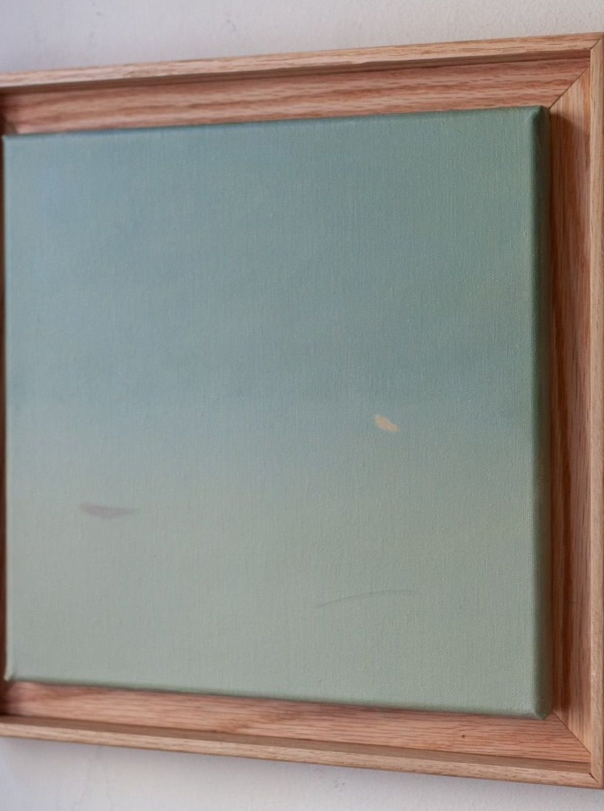 A framed canvas painting featuring a simple gradient from blue to green, with minimal markings and an overall abstract style. "Untitled, painting, 2024" by Rebecca von Matérn. The frame is crafted from hand-waxed oak, adding a touch of rustic elegance and highlighting the artist's artistic prowess.