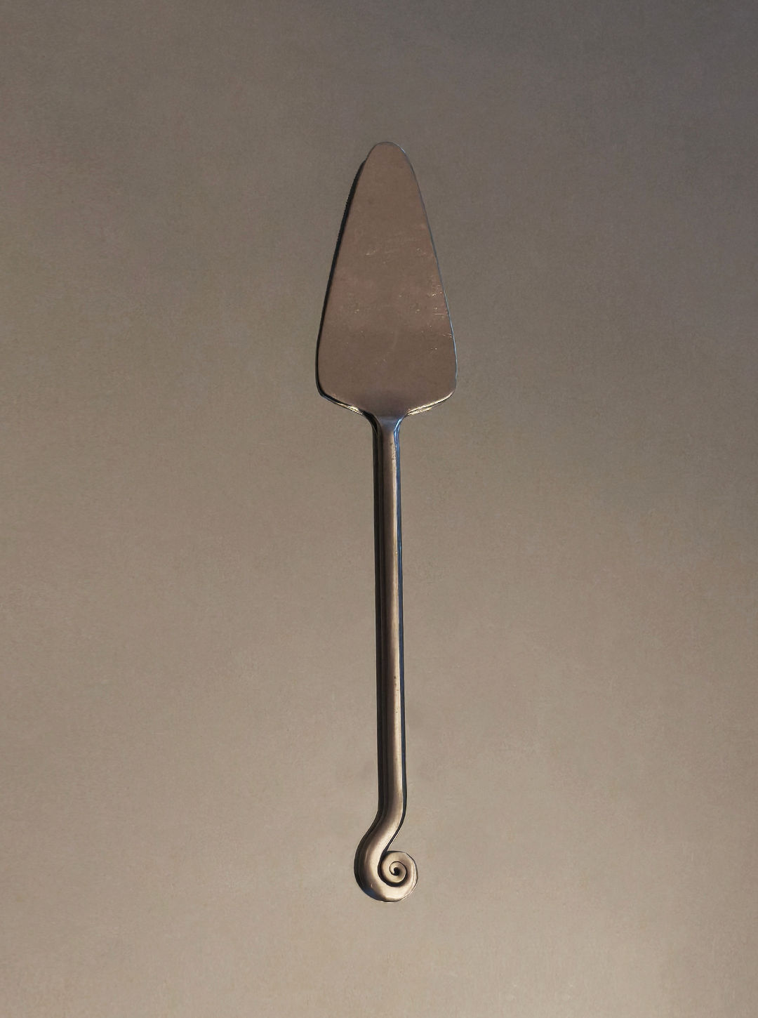 Spiral cake server with curved handle detail on neutral background