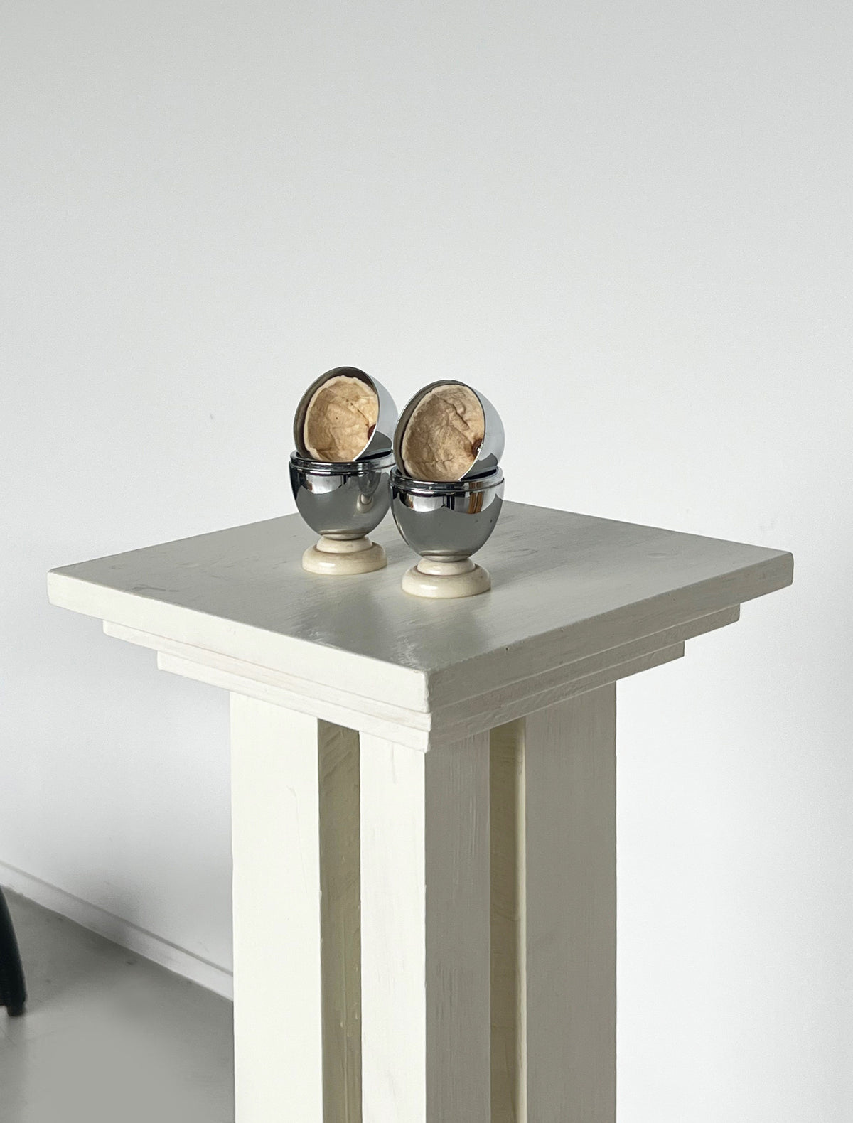 Pair of chrome Art Deco egg warmers with walnuts on white table