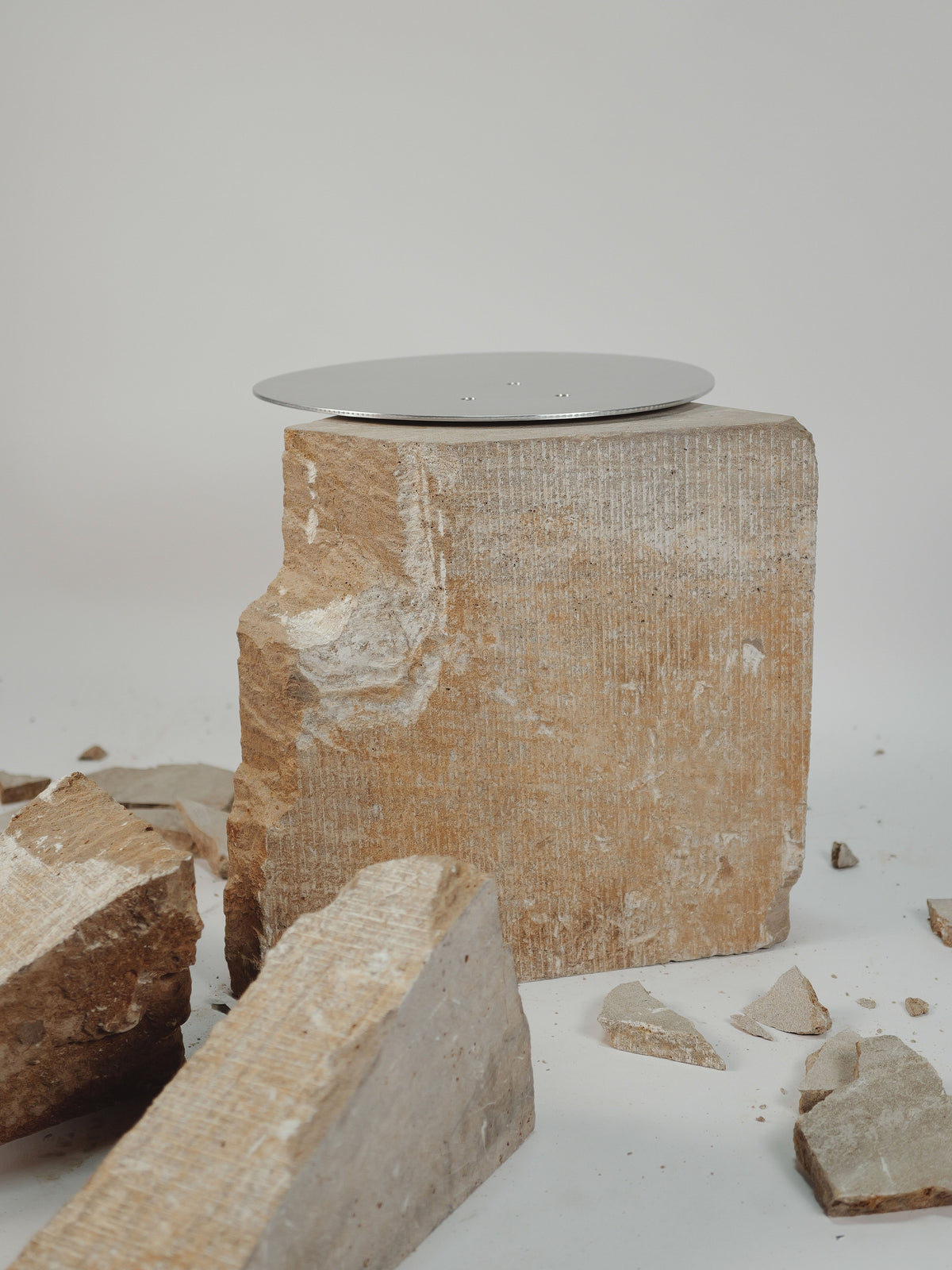 Fragments side table showing rough-hewn stone base with reflective metal top