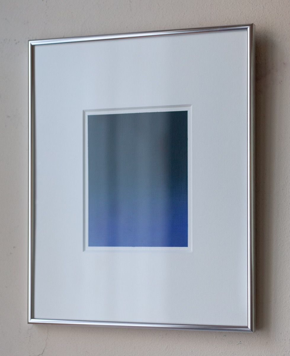 The "Untitled, 2024" painting by Rebecca von Matérn is a framed artwork showcasing a square with a gradient that transitions from deep blue at the bottom to lighter blue at the top. It is mounted on a wall in a simple aluminum frame, which complements the white mat surrounding this captivating art print.