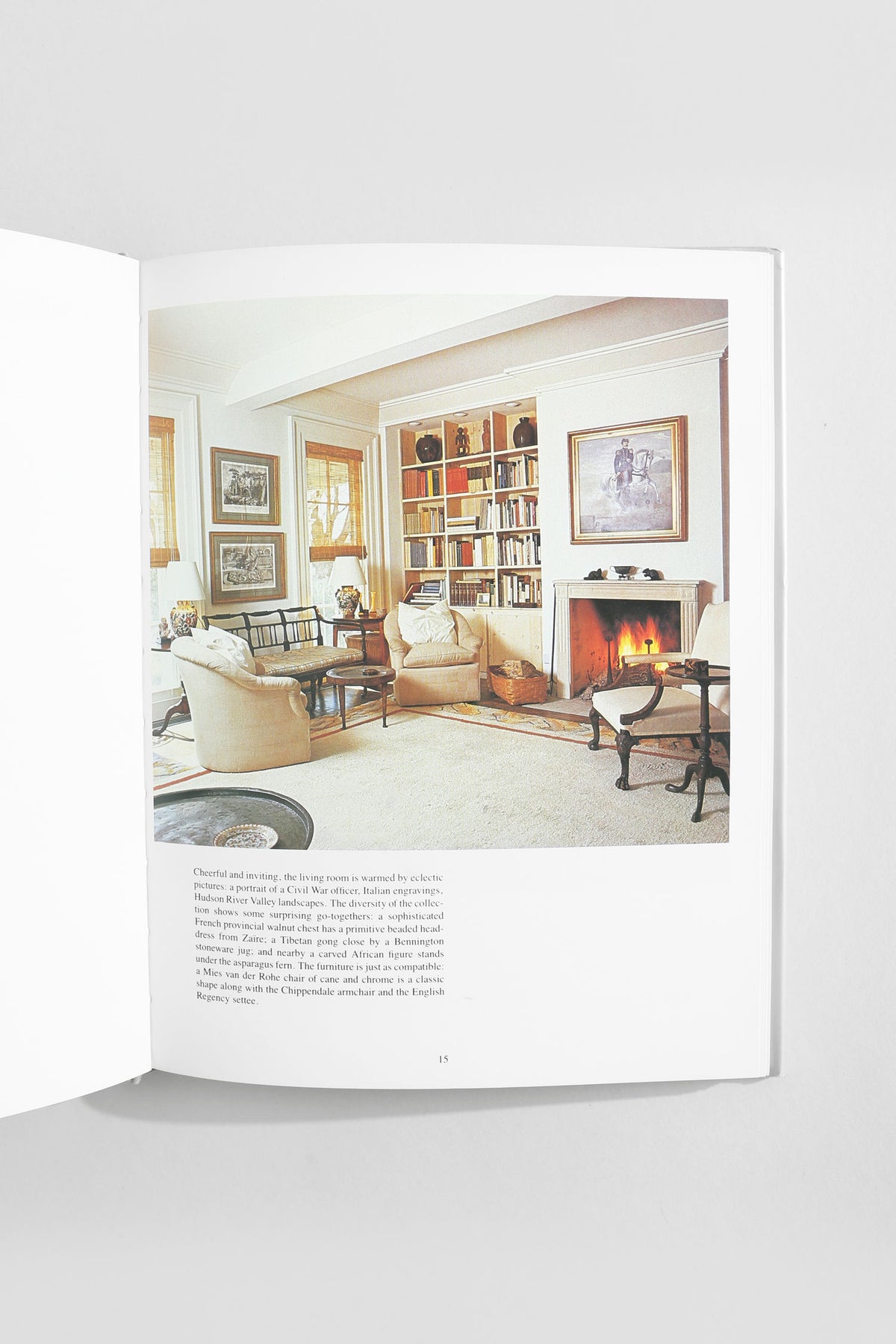 Open interior design book showing elegant living room with fireplace and built-in bookshelves