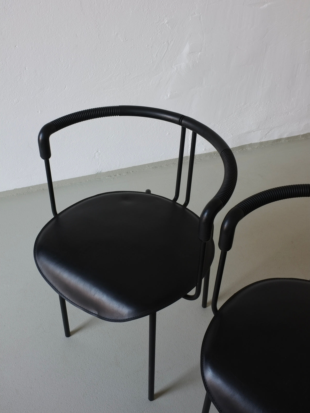 Postmodern black leather armchair with curved metal frame detail