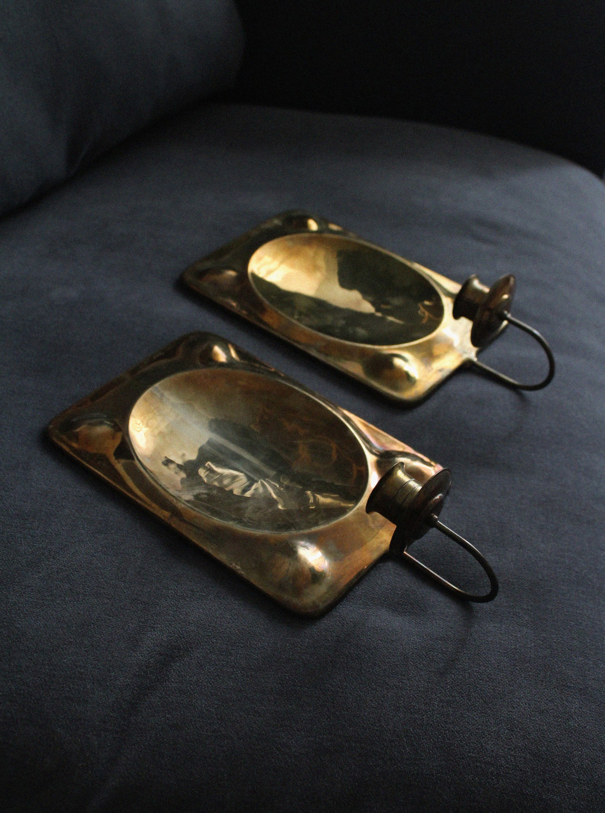 Brass wall sconces pair with reflective mirror backs, detail view