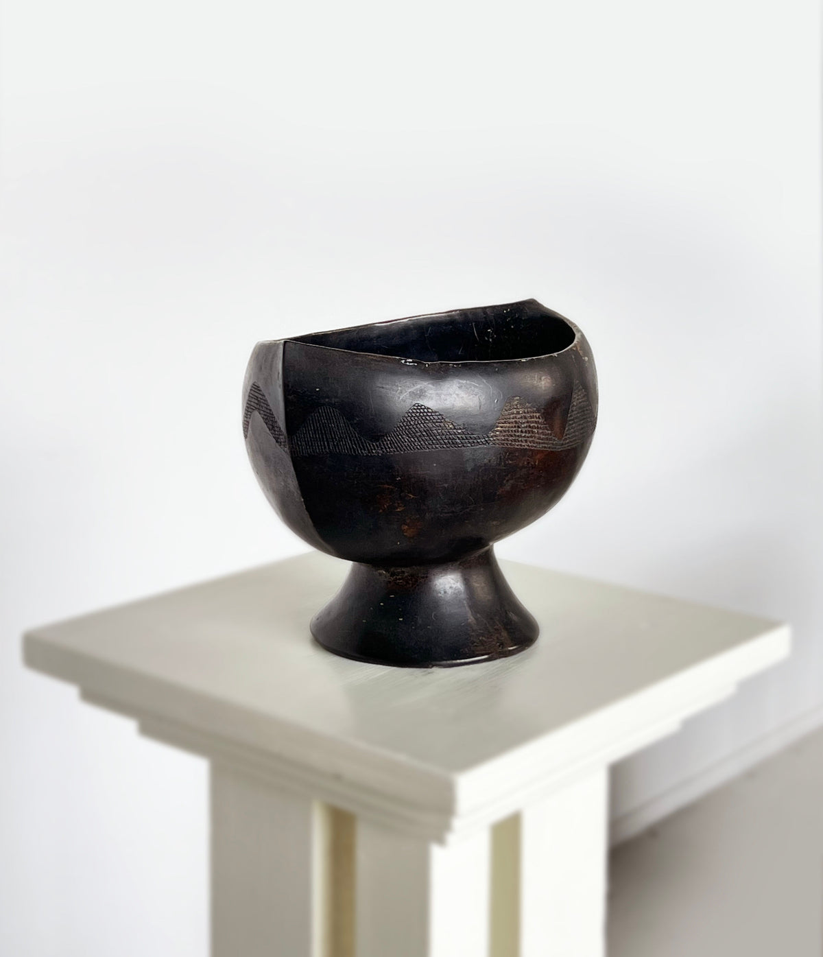 Dark ebony carved dish with geometric patterns on pedestal base