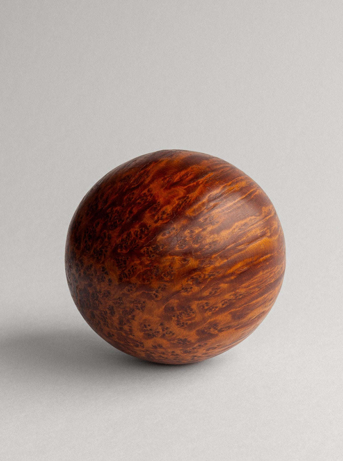 The Vintage Burl Wood Spherical Ball Sculpture by Spigel is a round, wooden ball crafted from Thuya burl wood, showcasing a smooth, polished surface and a rich, dark brown grain pattern. Placed against a gray background with subtle shadows, this handcrafted piece highlights its texture and natural wood variations, making it a stunning decorative accent.