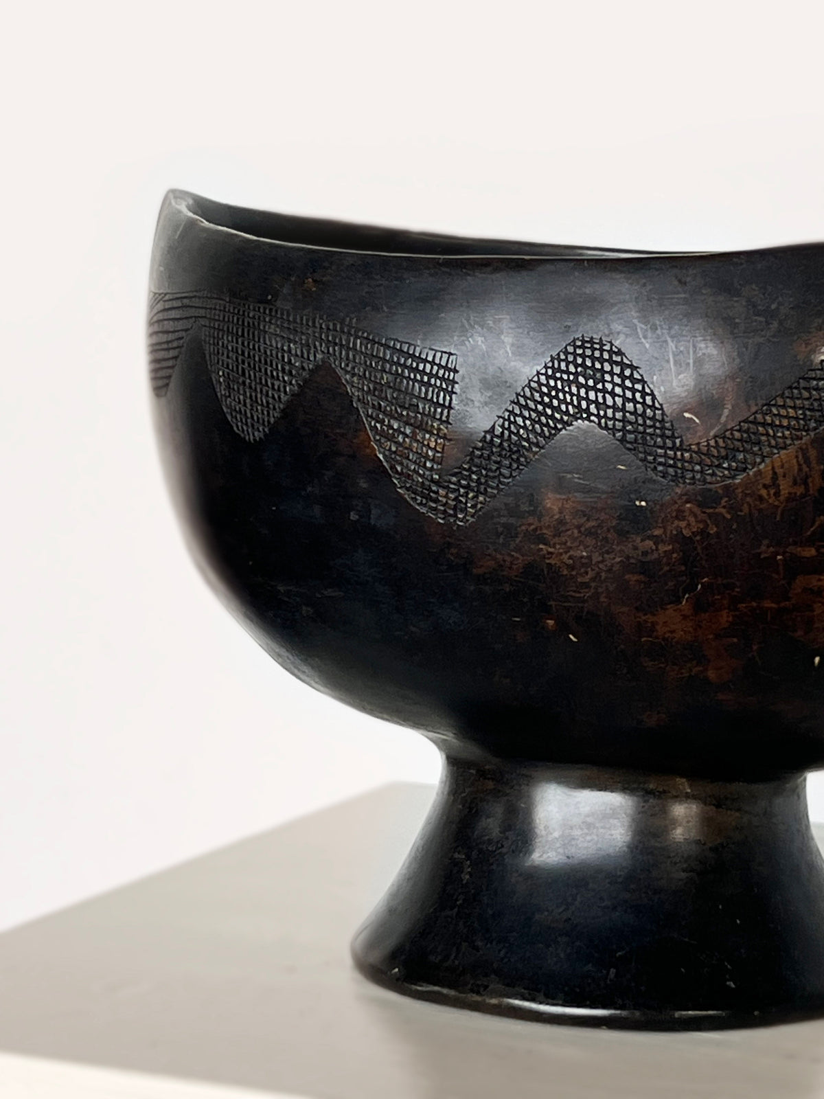 Detail view of ebony carved dish showing serpentine pattern