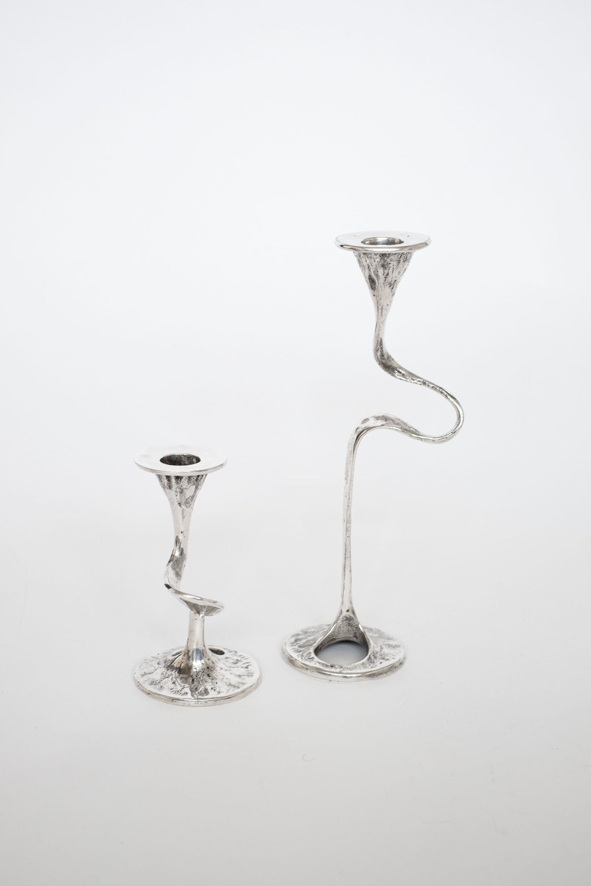 Curved silver-plated candle holders showing sculptural stems