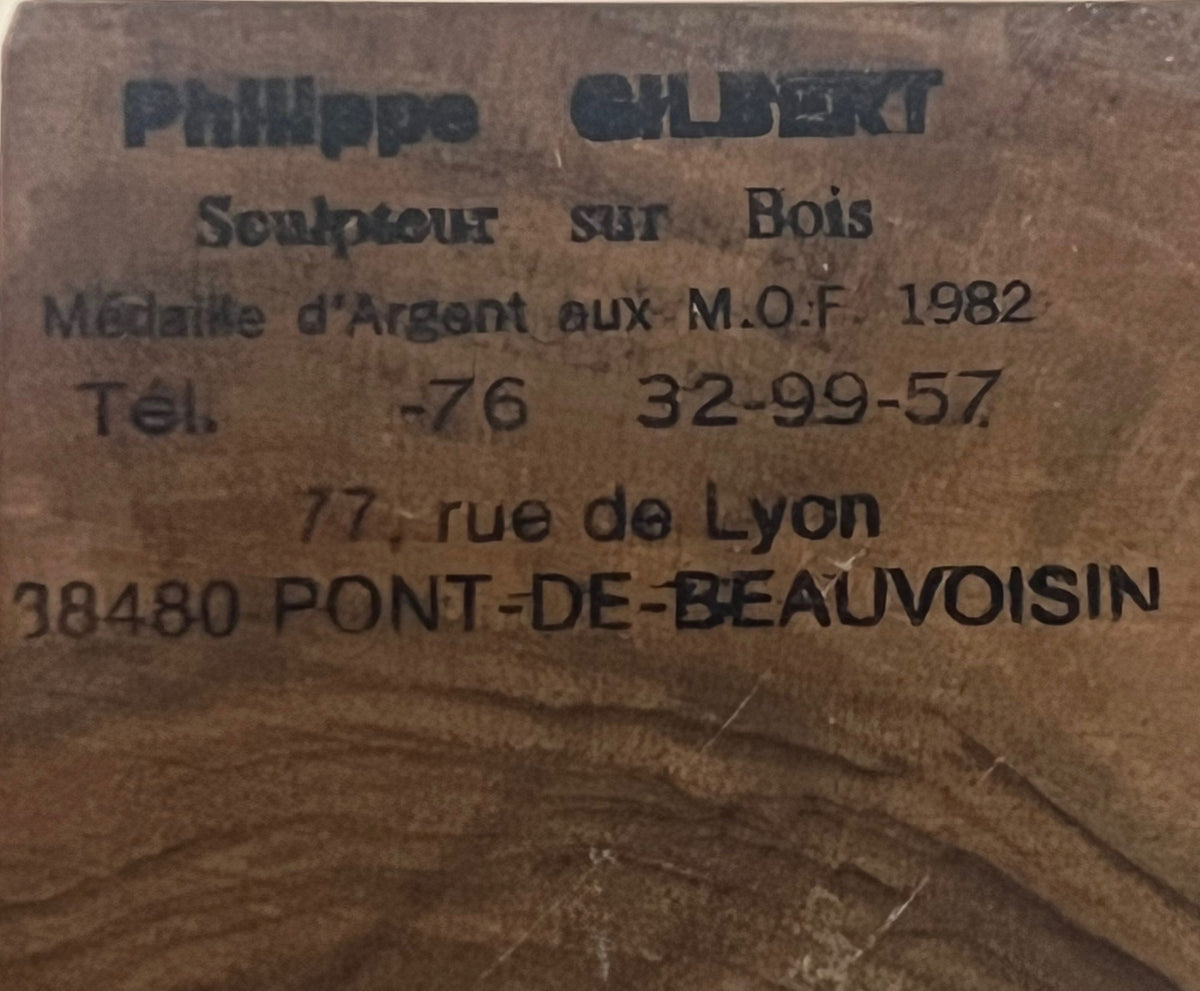 Wooden plaque featuring contact details for Philippe Gilbert, the acclaimed wood sculptor behind the Yin Yang Orb sculpture by Porter Studio. It emphasizes his 1982 silver medal achievement and displays the address as 77 rue de Lyon, 38480 Pont-de-Beauvoisin, with a partially visible phone number.
