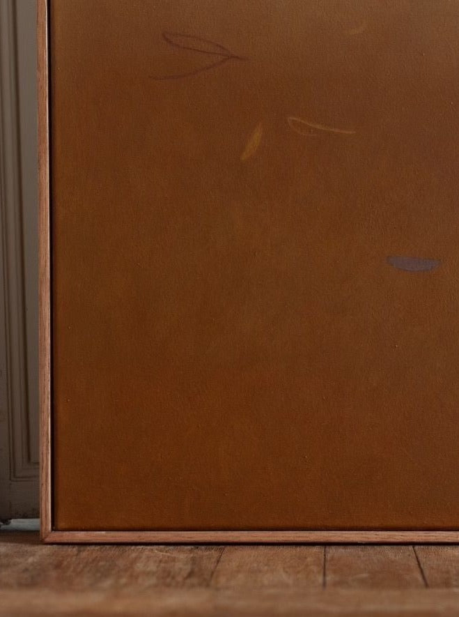 A minimalist painting, 82x102 cm, is presented in an oak frame on a wooden floor. The artwork consists of a solid, muted brown color with a few faint, abstract strokes in different shades. The background and surroundings are simple, focusing attention on the acrylic on canvas painting "Something(s) in the air, 2024" by Rebecca von Matérn.