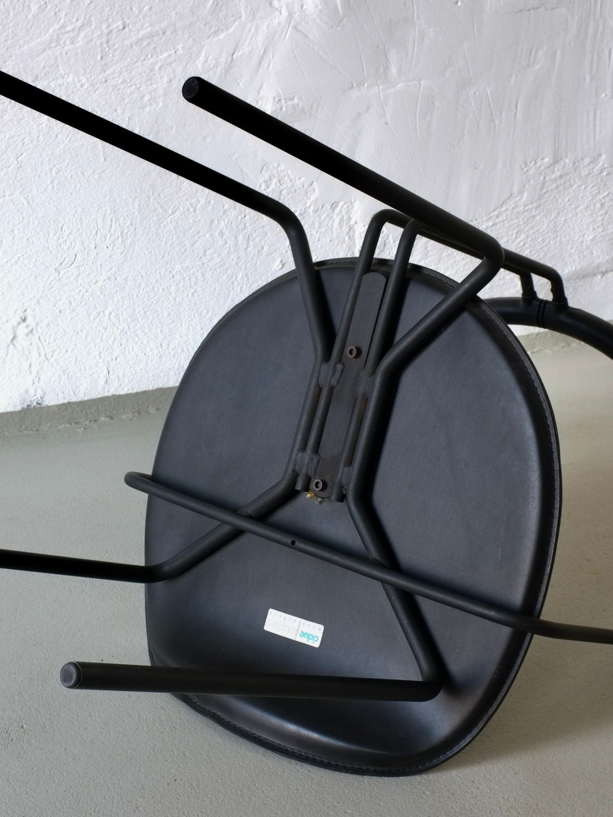 Underside view of black leather Cidue postmodern armchair frame