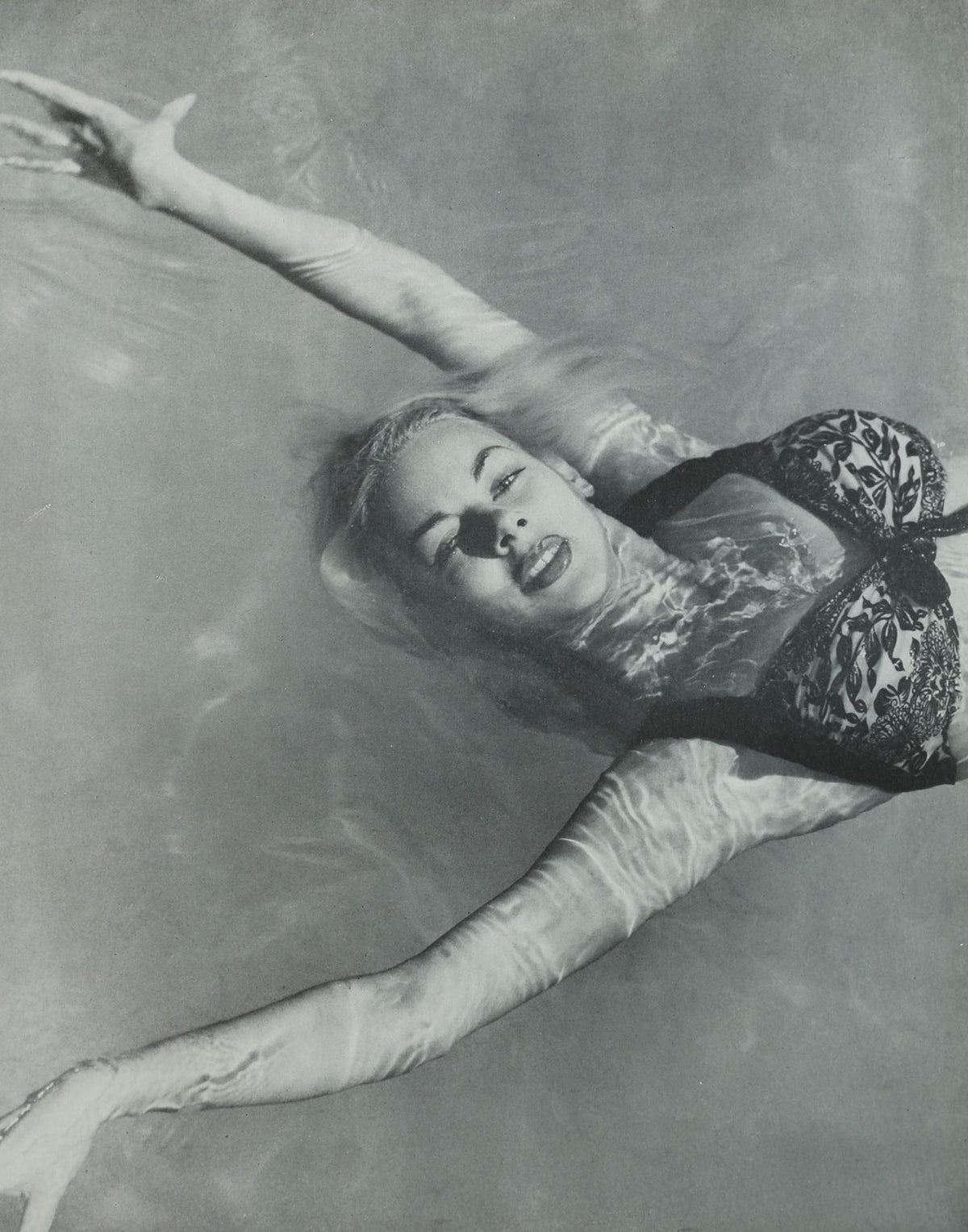 Woman laughing while reading Photography is a Language book in water