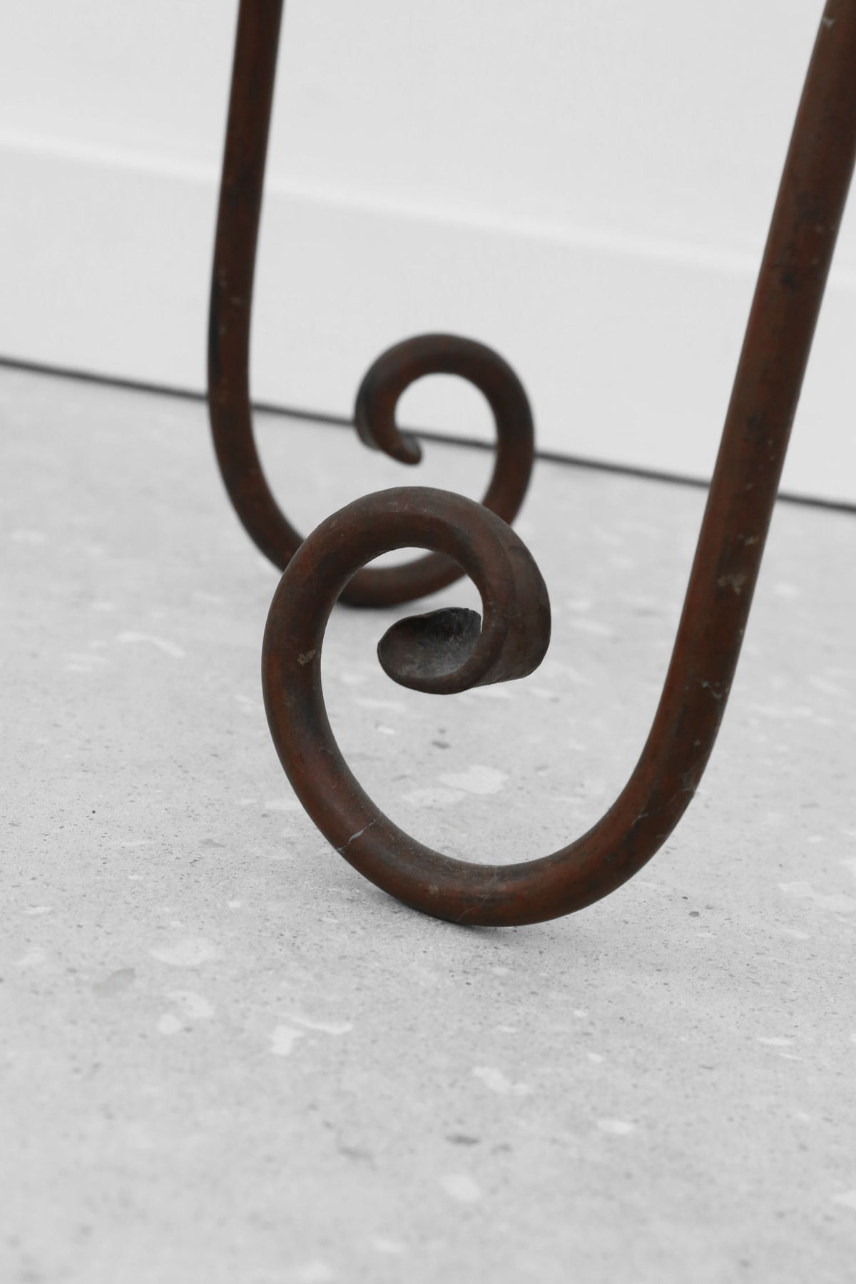Iron candleholder base detail showing curved decorative scrollwork