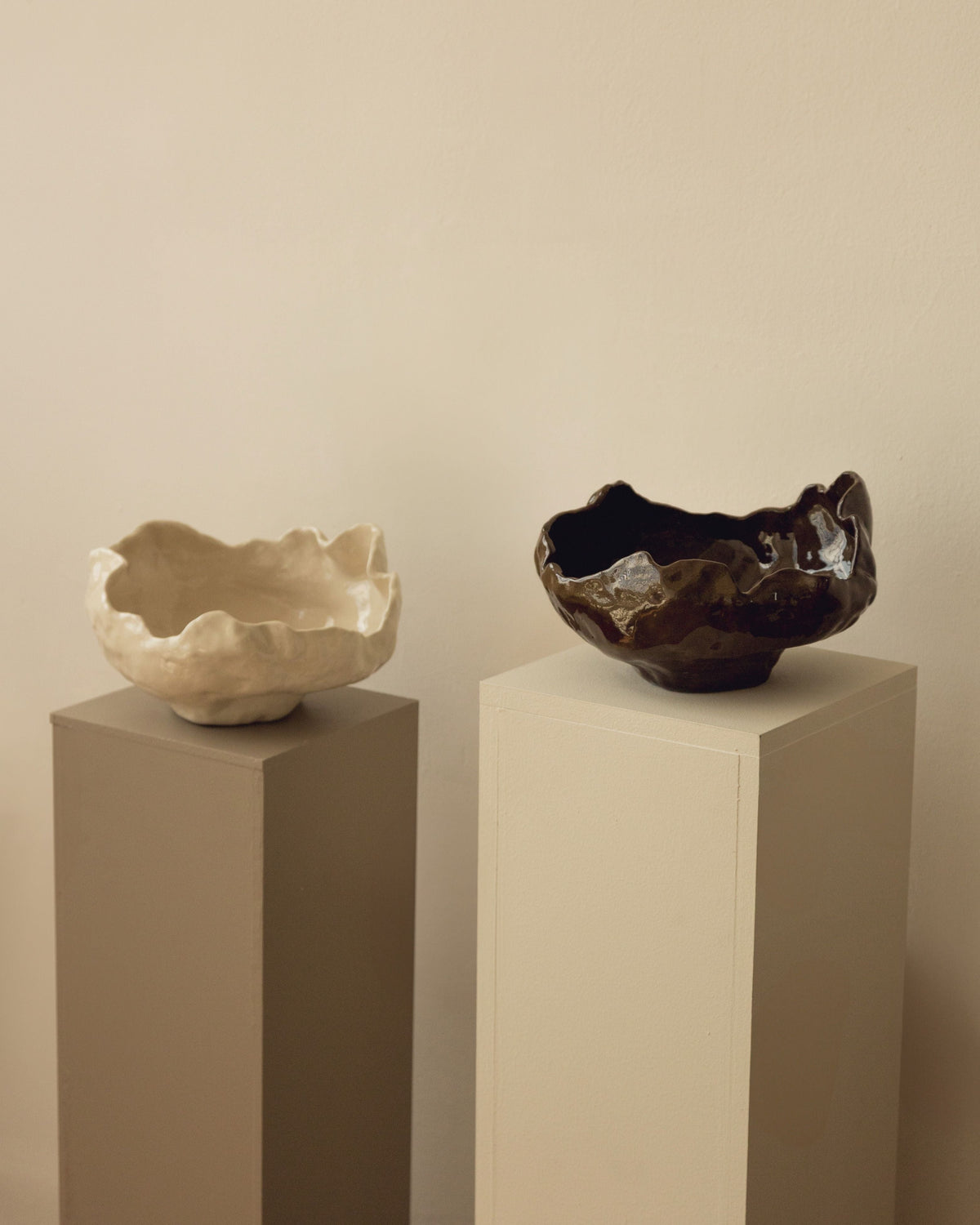 Two Modica ceramic bowls with organic wavy edges on display pedestals