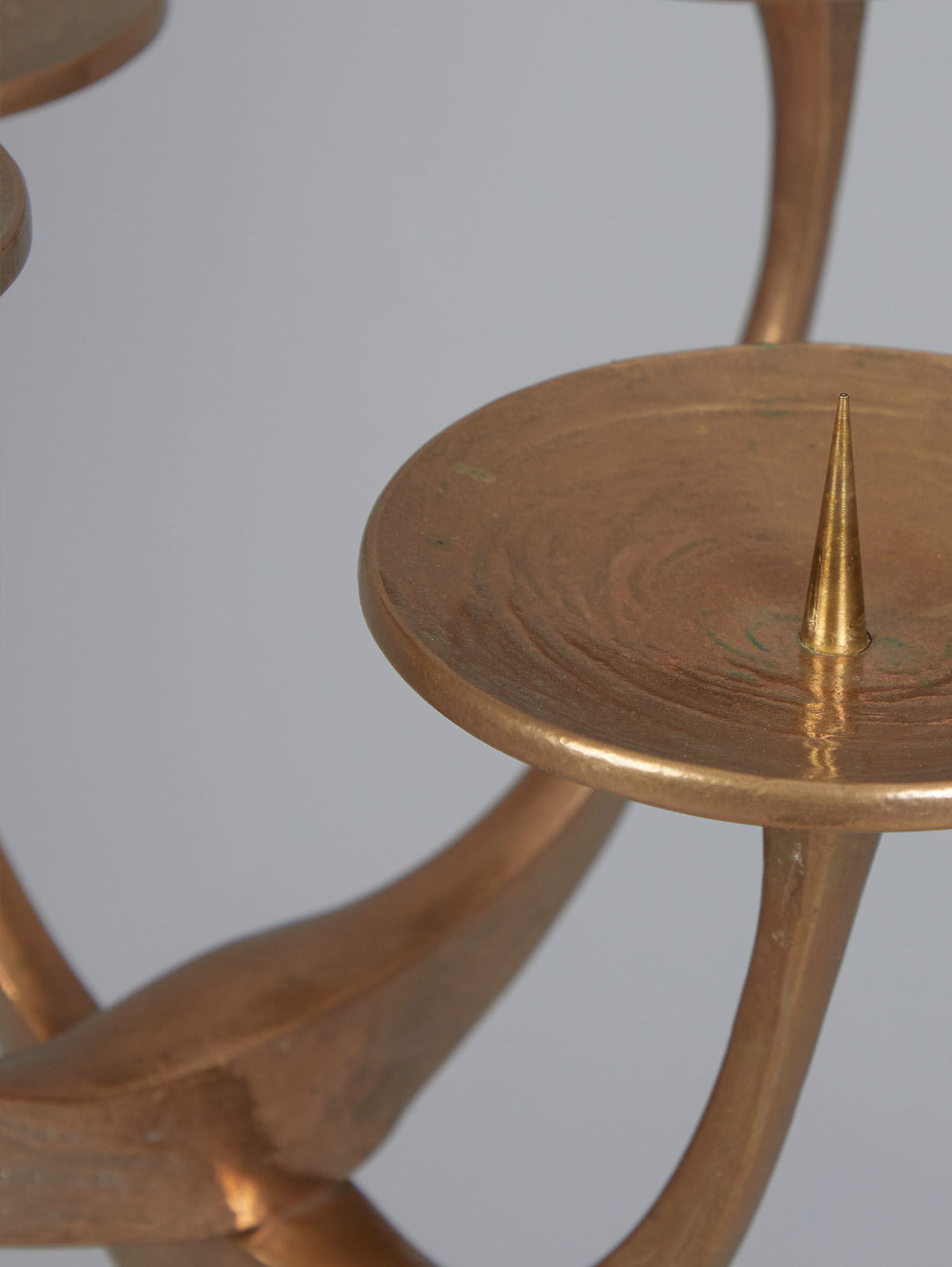 Close-up of the Floor Standing Brutalist Candleholder by Tobias Harjes from RELIC LONDON, showcasing a round platform with a central spike and graceful curved arms for an artistic, elegant look against a light gray background.
