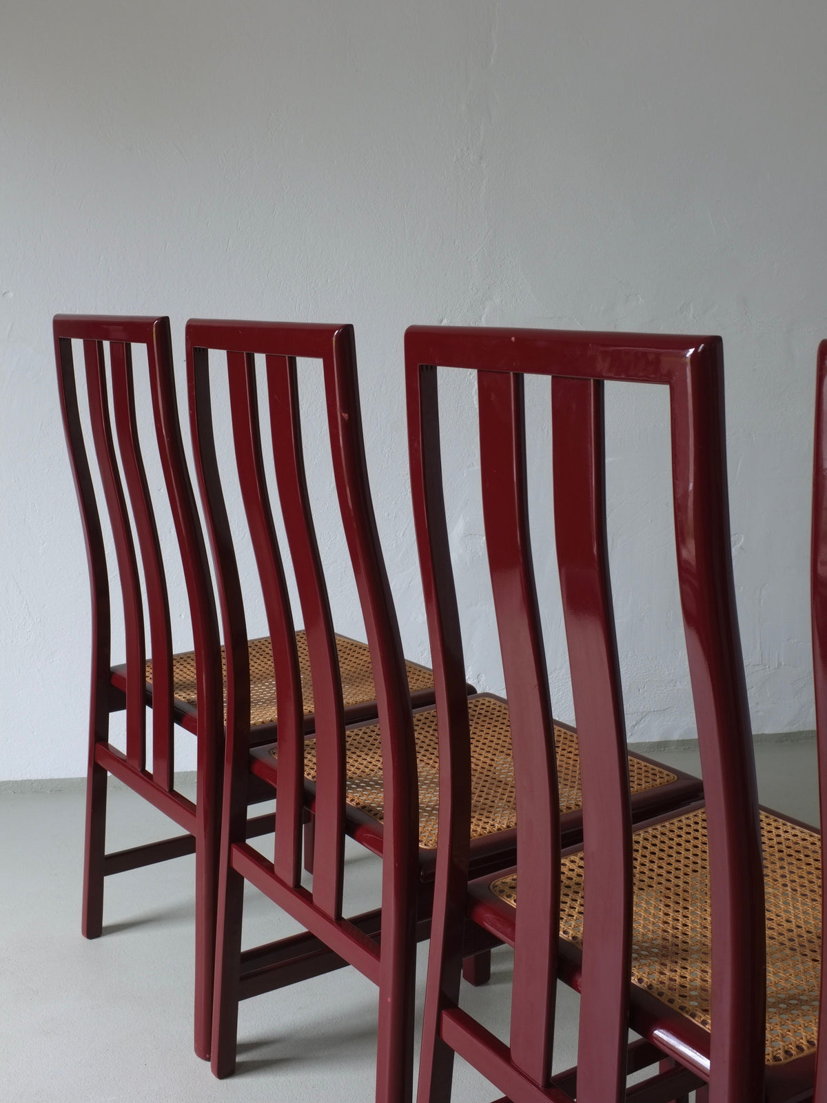 Glossy wine red chairs with cane seats stacked, Italian 1970s design