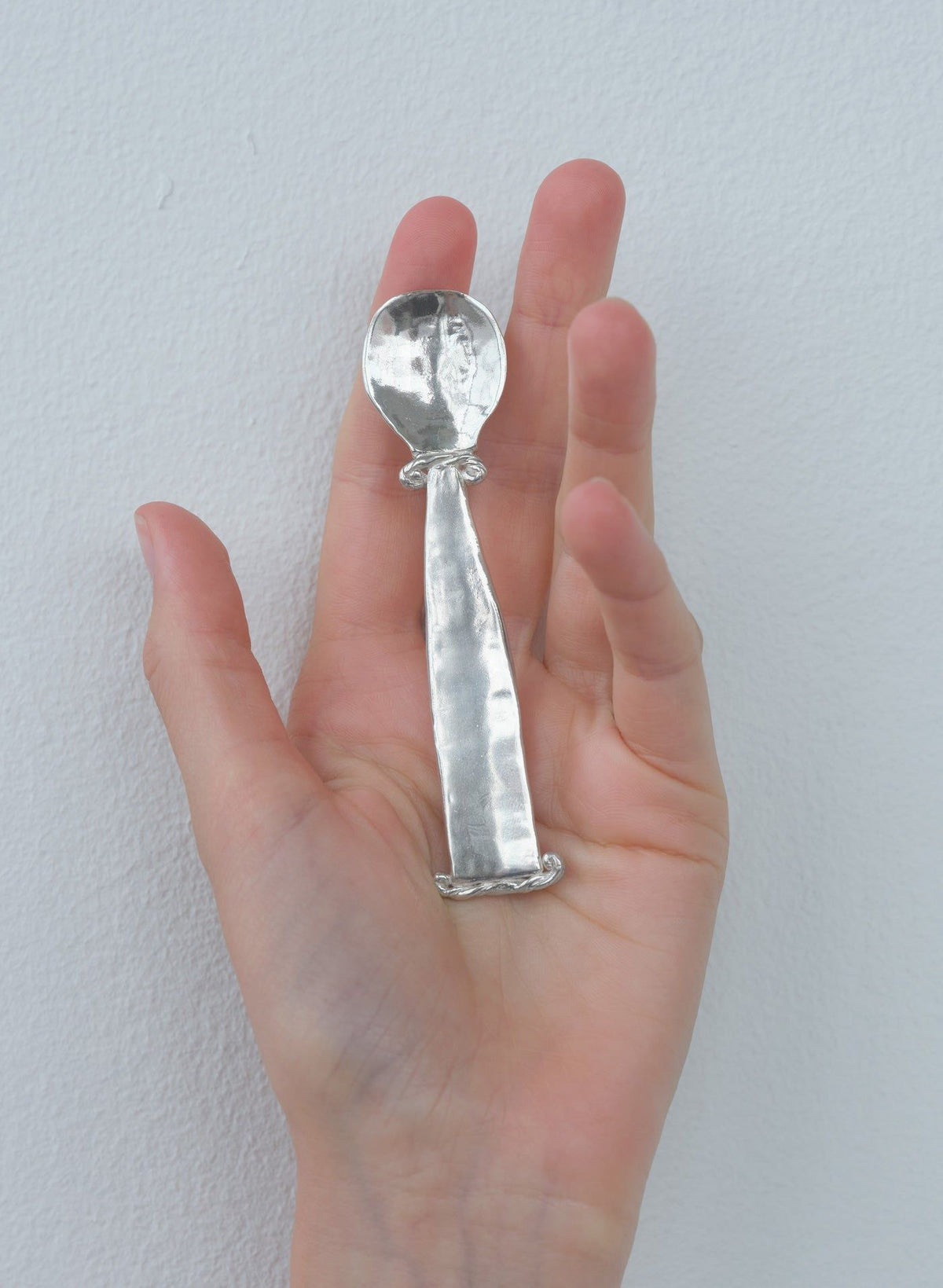 Hand holding silver Jakob spoon showing detailed craftsmanship