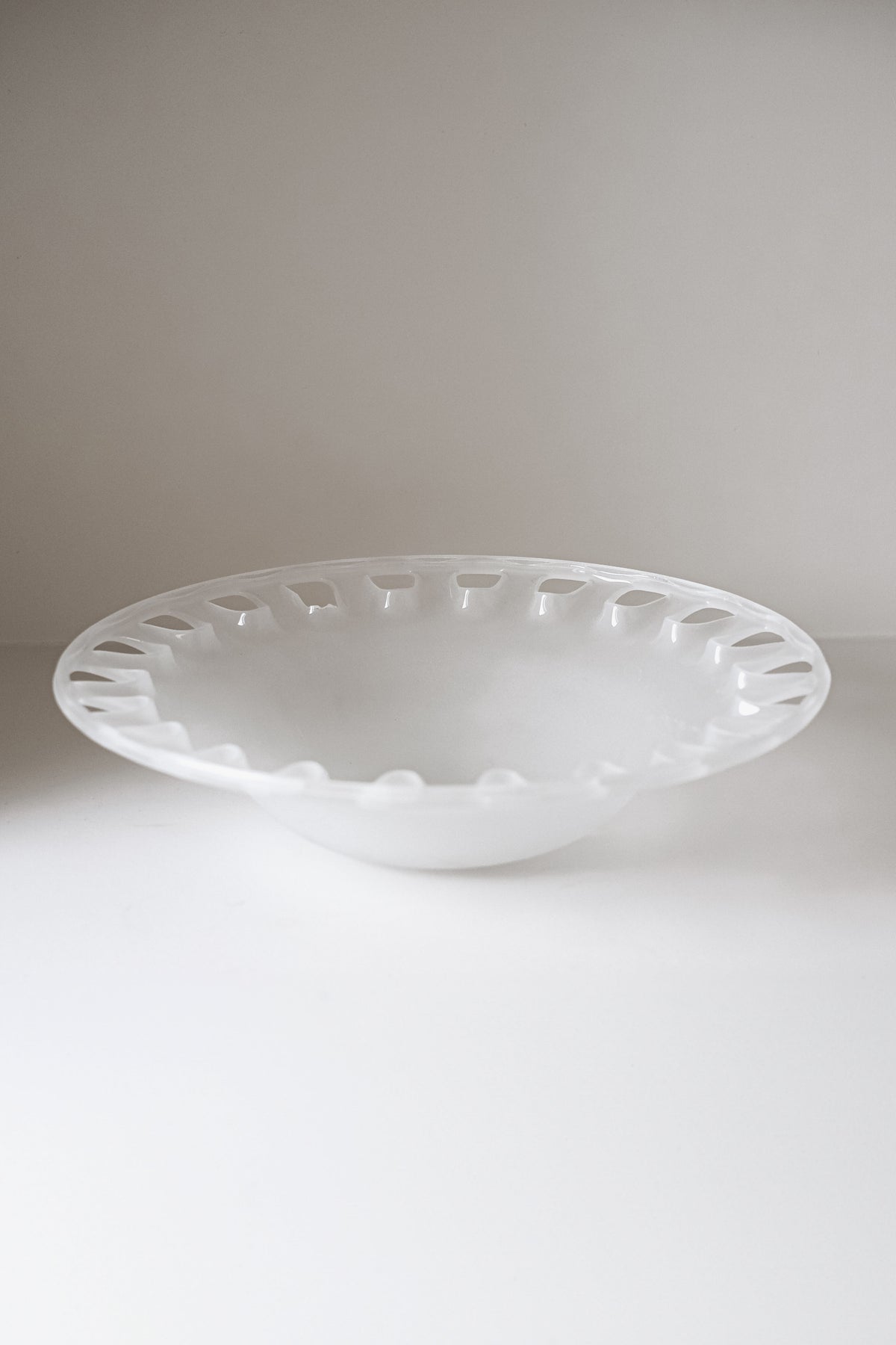 The Large Bowl of Milk Glass by septembre studios is a glossy white ceramic bowl with a wide rim featuring evenly spaced raised bumps against a plain background.