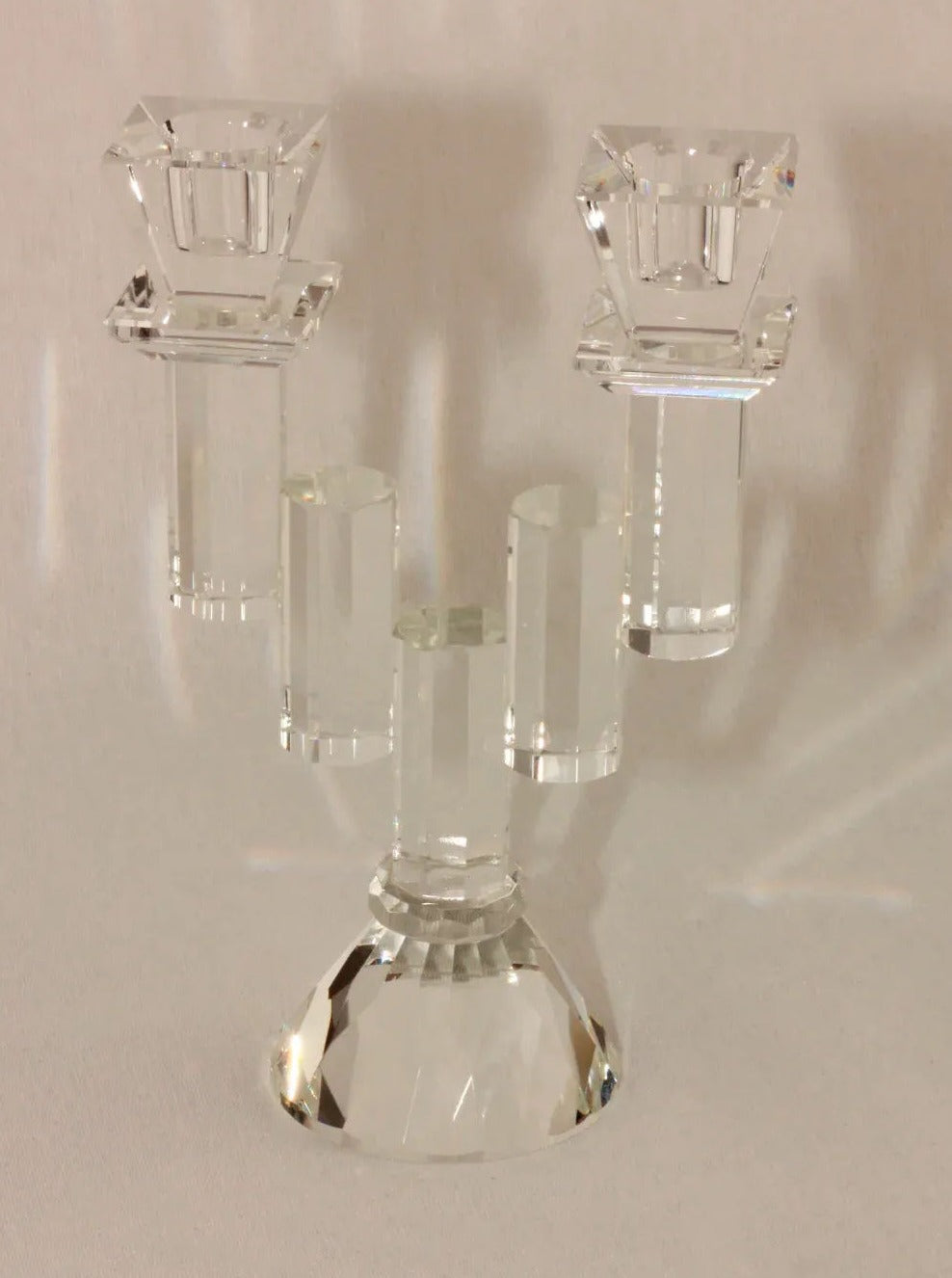 A Faceted Crystal Candleholder by Boga Avante Shop is elegantly displayed against a plain white background. Resembling a vintage item, its central holder is slightly taller than the two side holders, all supported by a sturdy, faceted base.