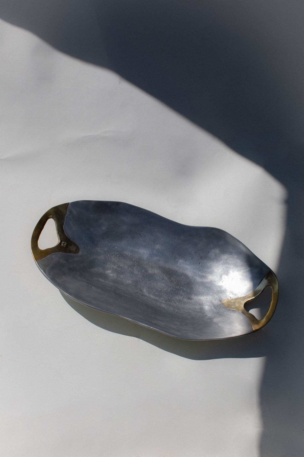 Brutalist bowl with brass handles shown at an angle on white surface