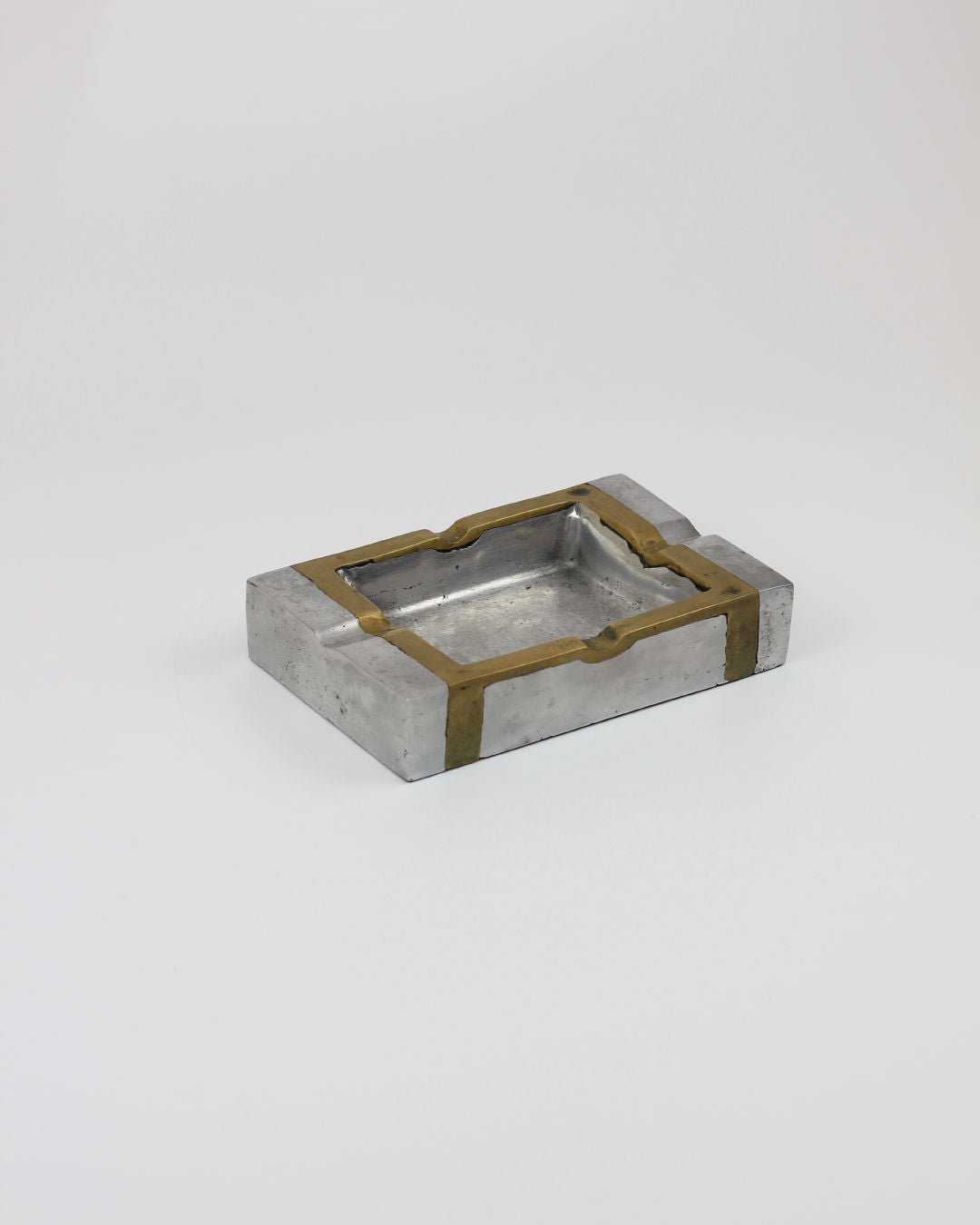 The Brutalist Ashtray 70s by Boga Avante Shop features a rectangular metallic design with silver and gold accents, made in Spain, and is showcased against a plain white background.