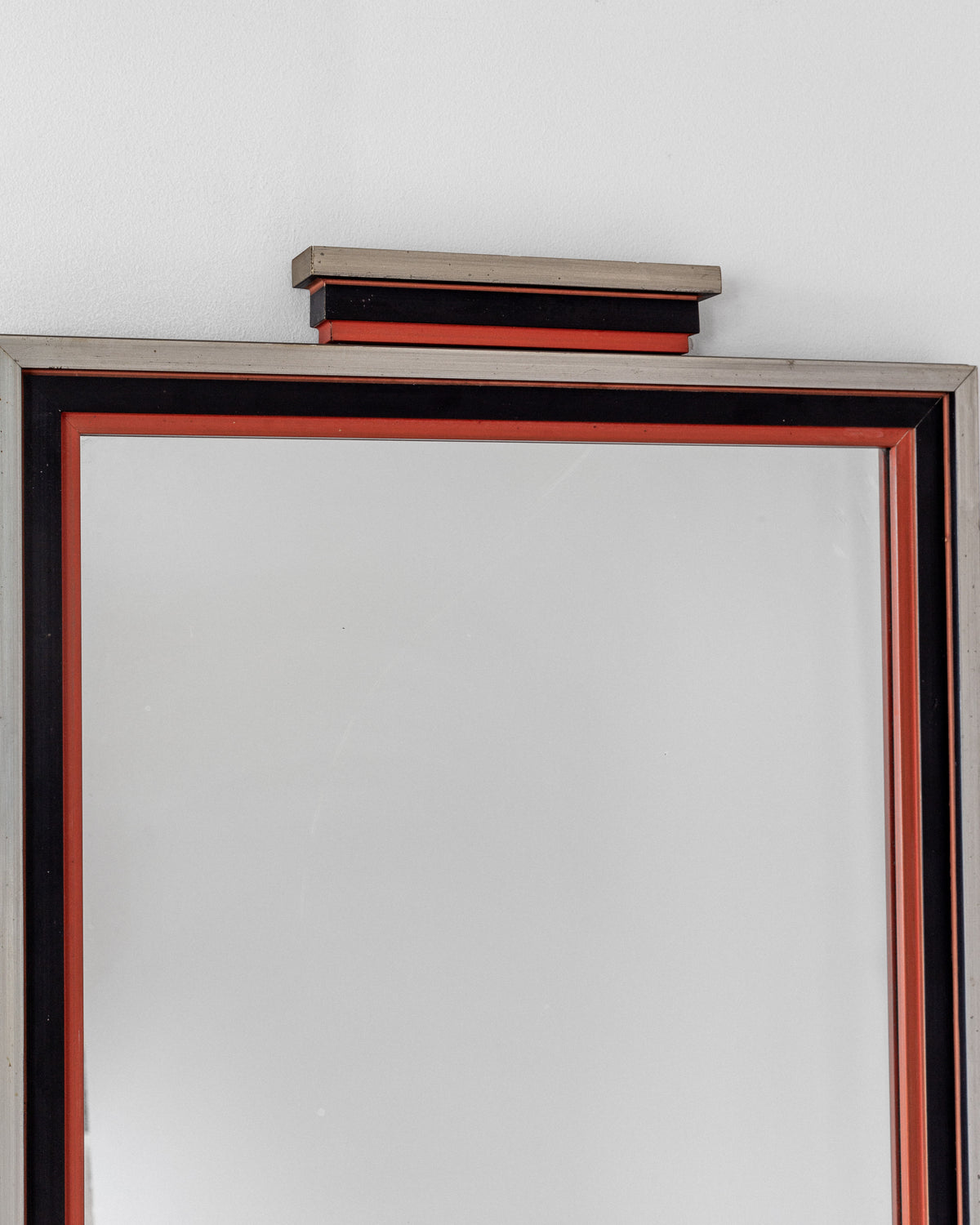 The Art Deco Mirror from 1930s Sweden by Spigel showcases a rectangular, layered frame with red, black, and metallic silver accents. Its sleek design adds vintage charm with a decorative top block against a plain white wall.