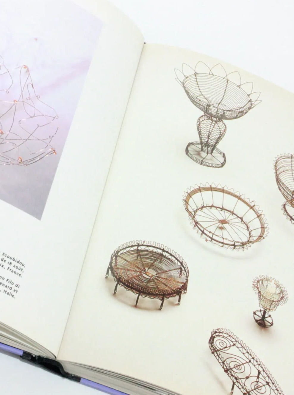 An open libro de tapa dura showcases intricate wireframe sculptures, including delicate bowls, baskets, and other decorative containers, arranged artistically on its pages. The sculptures vary in shape and size, demonstrating craftsmanship and diseño moderno en el Objets Affectifs: Le Nouveau Design de la Table de Boga Avante Shop.