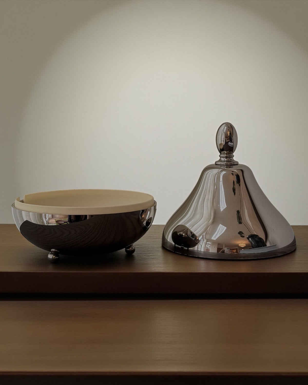 Pear-shaped chrome serving dome with matching bowl on wooden shelf