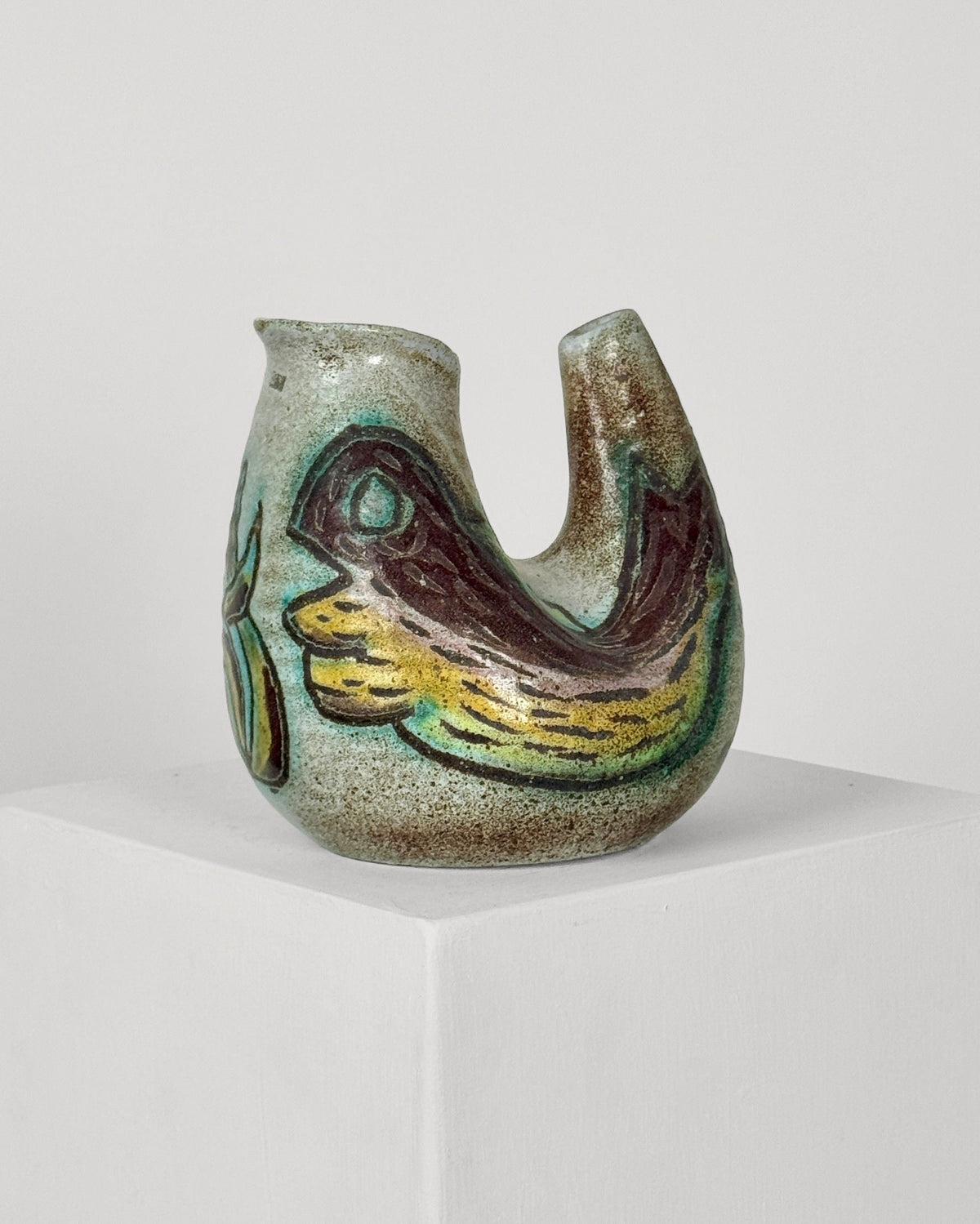 Zoomorphic ceramic vase detail showing abstract bird motif in earth tones