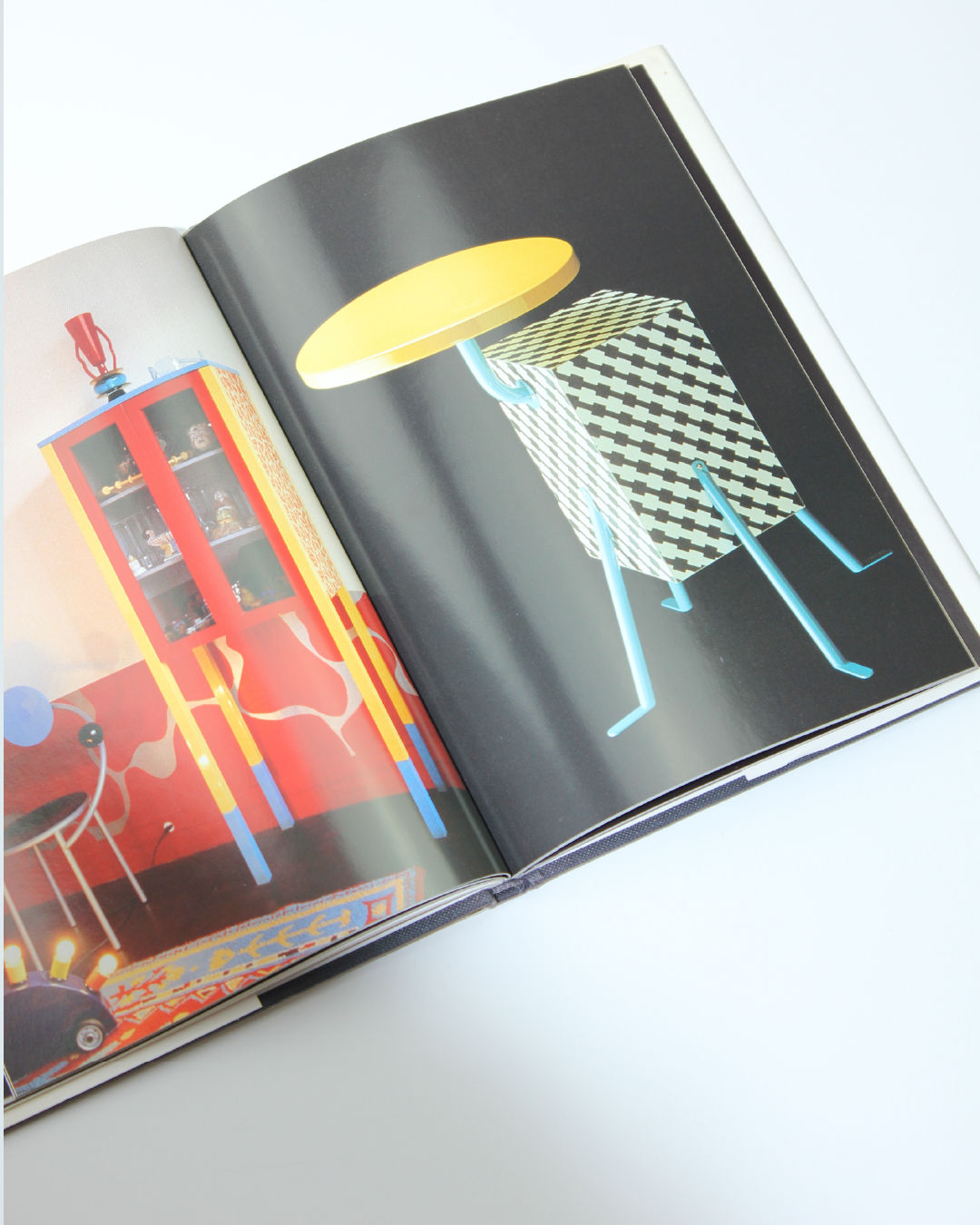 Memphis design book open showing colorful geometric furniture illustrations