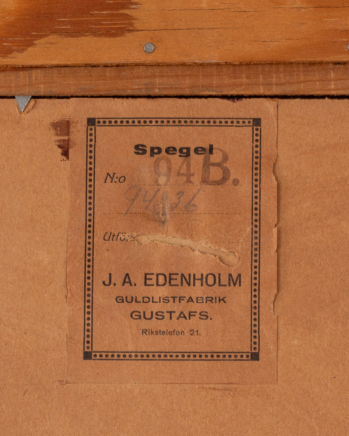 A slightly worn label on a wooden surface reads: "Spigel 94B. No: 746. Utf. J.A. Edenholm, Guldlistfabrik Gustafs, Rikstelefon 21." This vintage Art Deco mirror from the 1930s was crafted in Sweden by J.A. Edenholm, adding to its charming appeal.